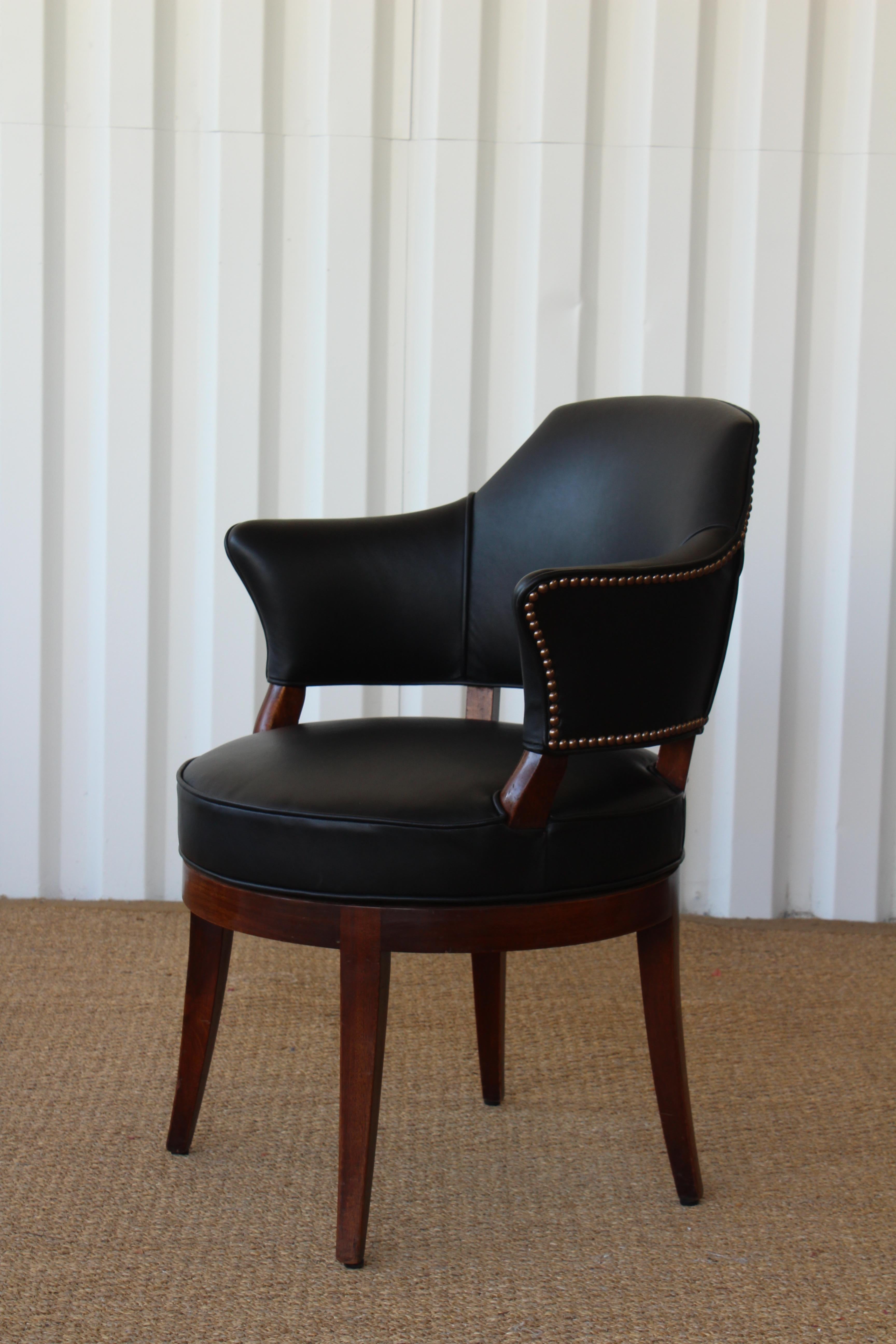 Walnut swiveling desk chair reupholstered in black leather with antique nailhead details. Chair rotates 360 degrees. Walnut frame shows minor signs of wear.