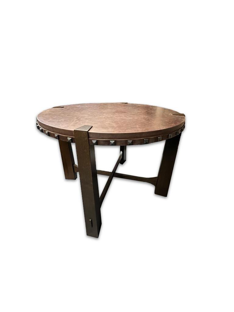 This unique leather studded wood table is an excellent statement piece. This piece has a soft leather circular top adorner with detailed nail heads in its perimeter, it has sturdy wooden legs that are joined at the center of the table. 

Property