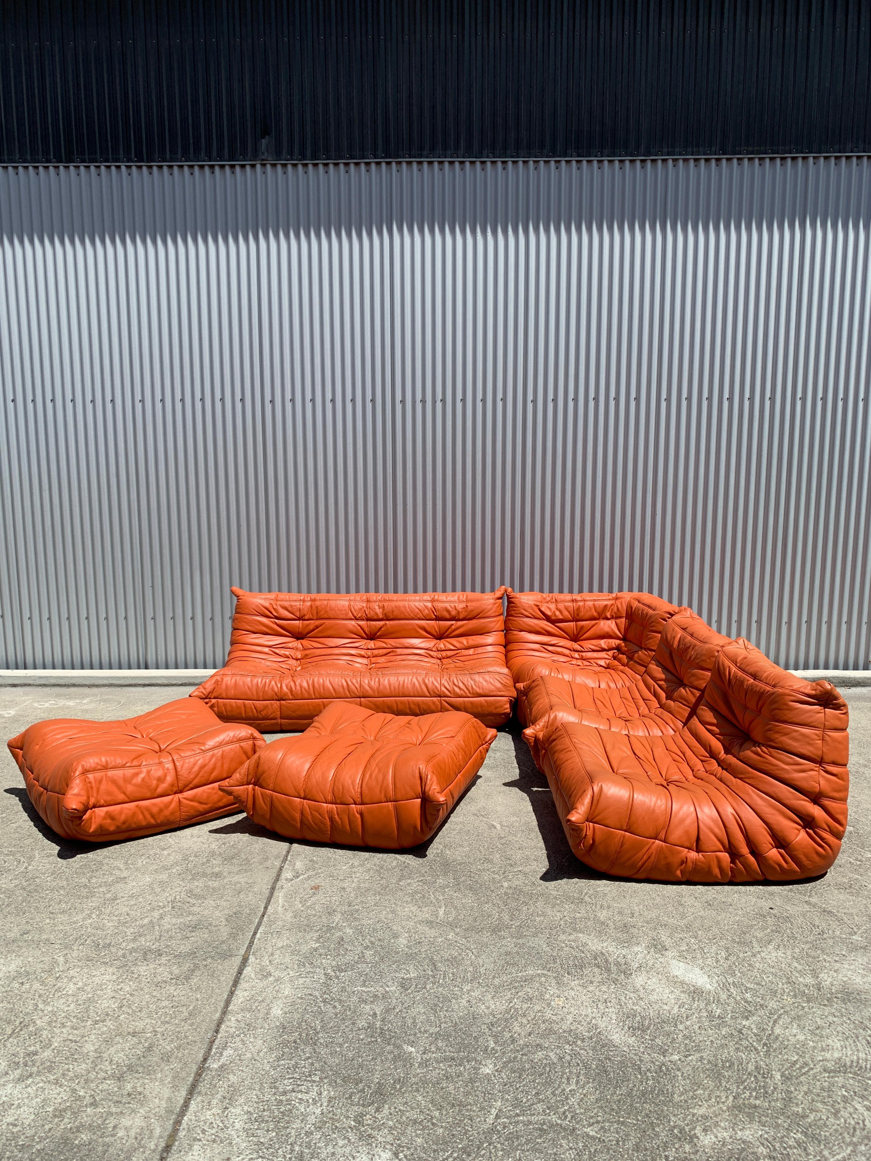 Beautiful vintage umber leather Michel Ducaroy Togo sectional by Linge Roset. Set of six pieces including two seat sofa, two armless chairs, corner, and two ottomans. Excellent overall condition with some mild finish crackling and chaffing on the