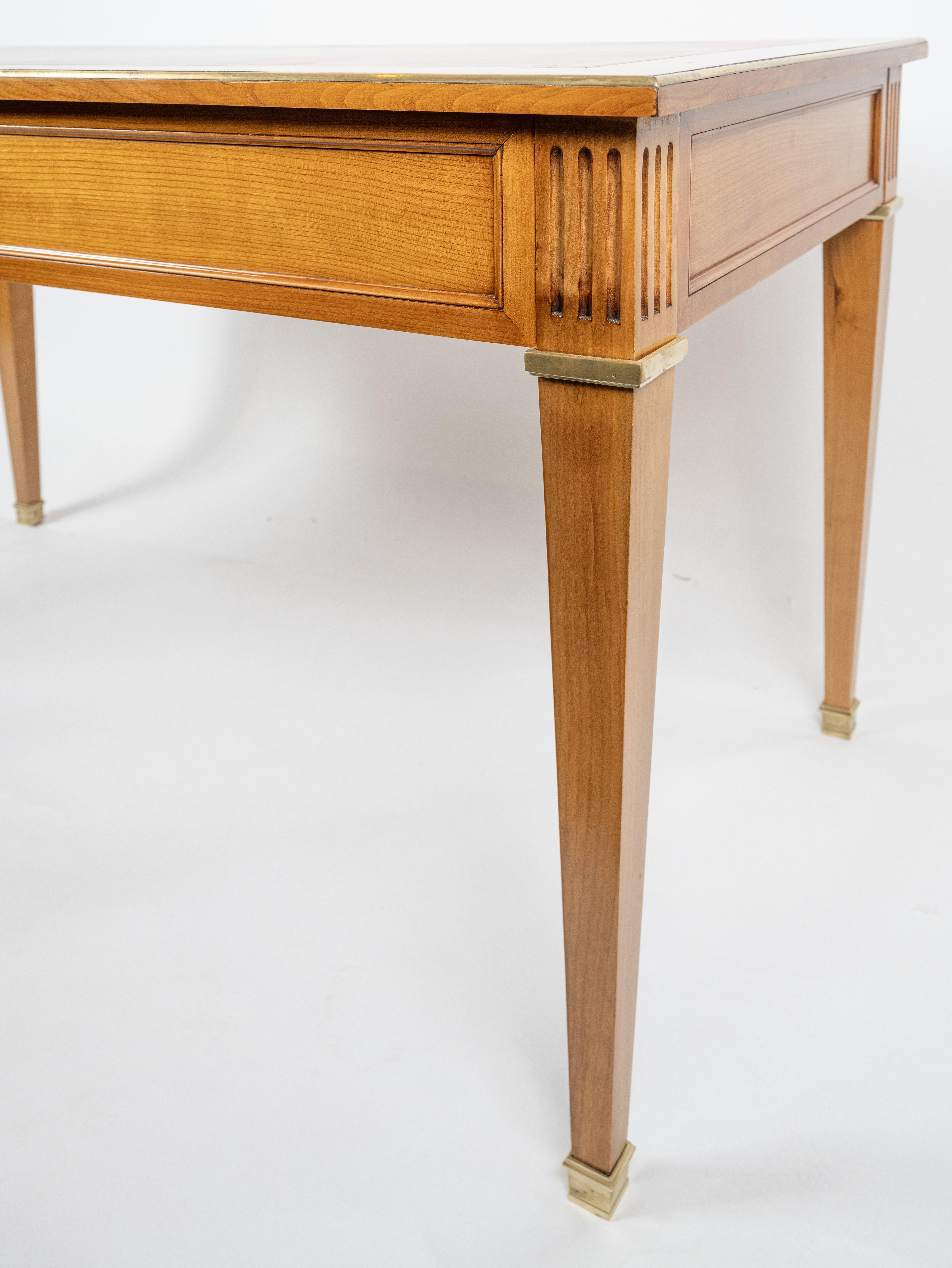 A French cherry writing table finished on four sides with three drawers. The square and tapered legs supported by an apron with molded edge trim. The top with cross band veneered sides and ends. having new inset tole leather  surface with foliate