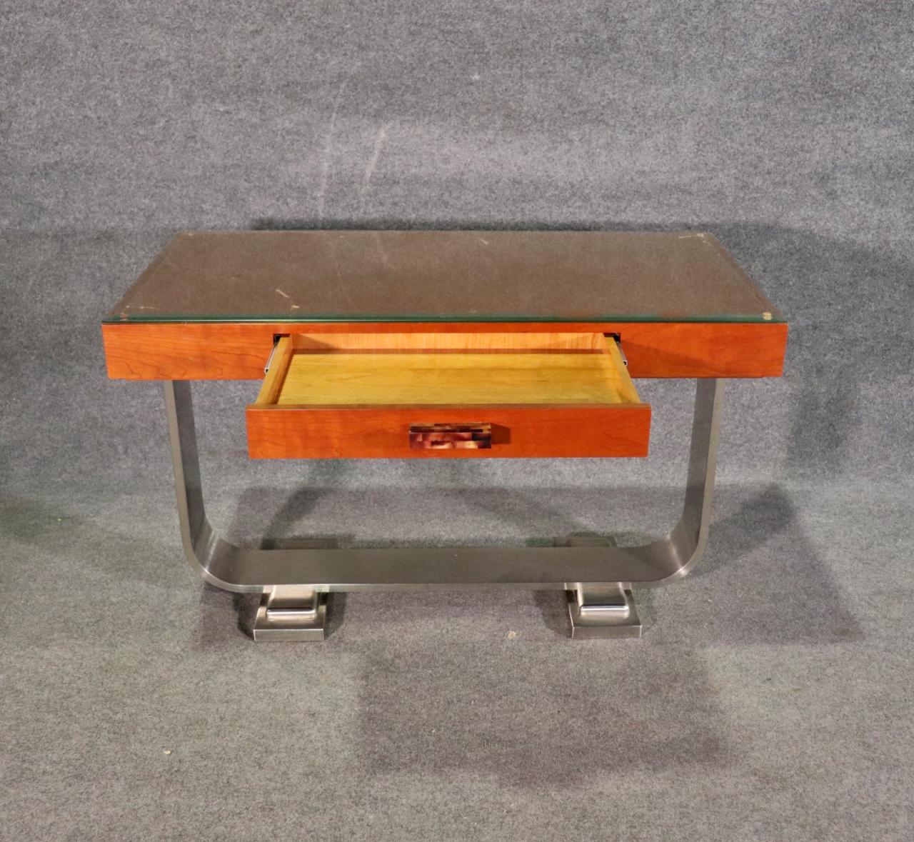Deco style desk on aluminum metal base with single drawer. Glass top protector over the leather writing surface. Drawer has an attractive acrylic handle.
Please confirm location NY or NJ