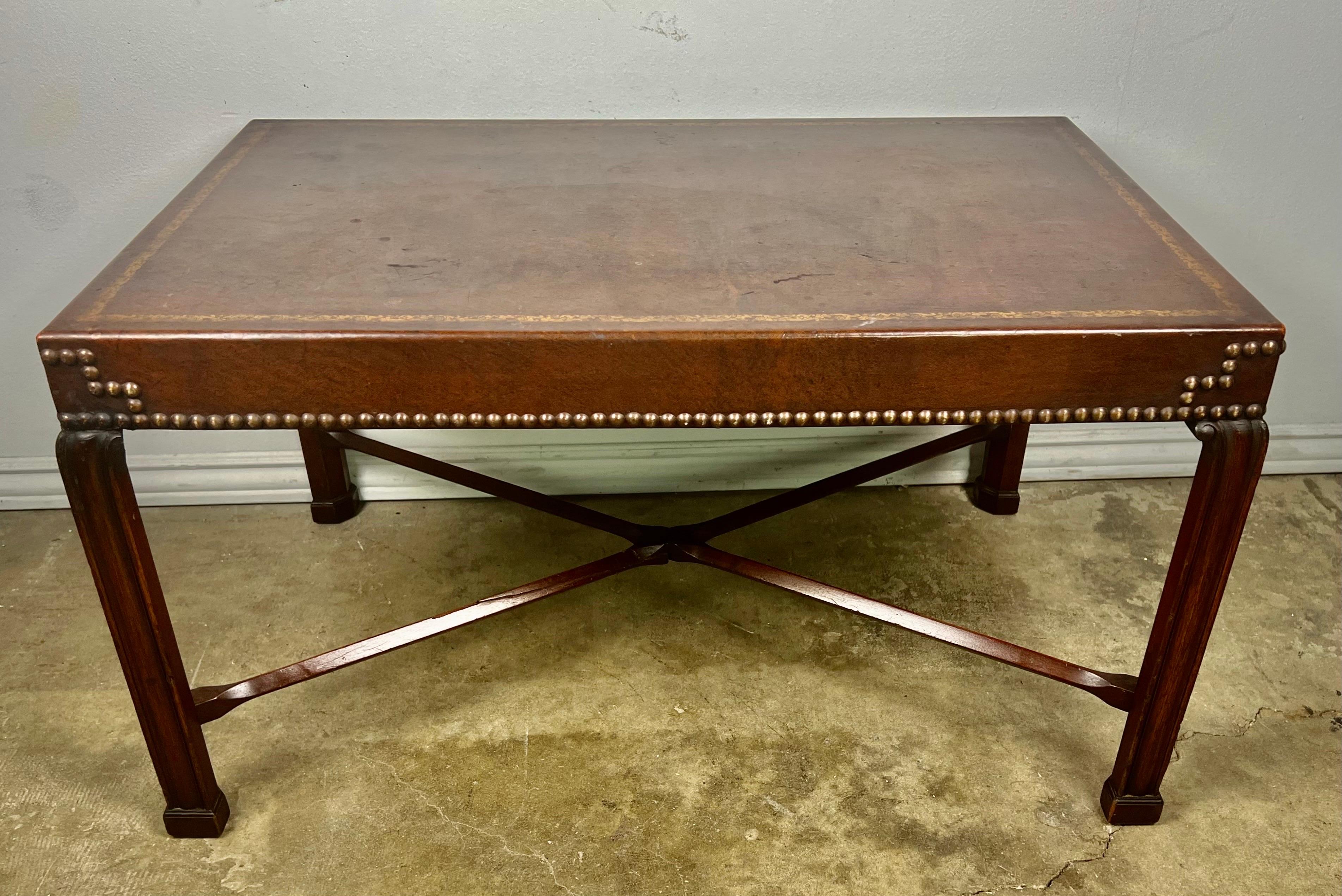 English Chippendale style mahogany tea table with a leather embossed top. The table stands on four straight legs connected by an 