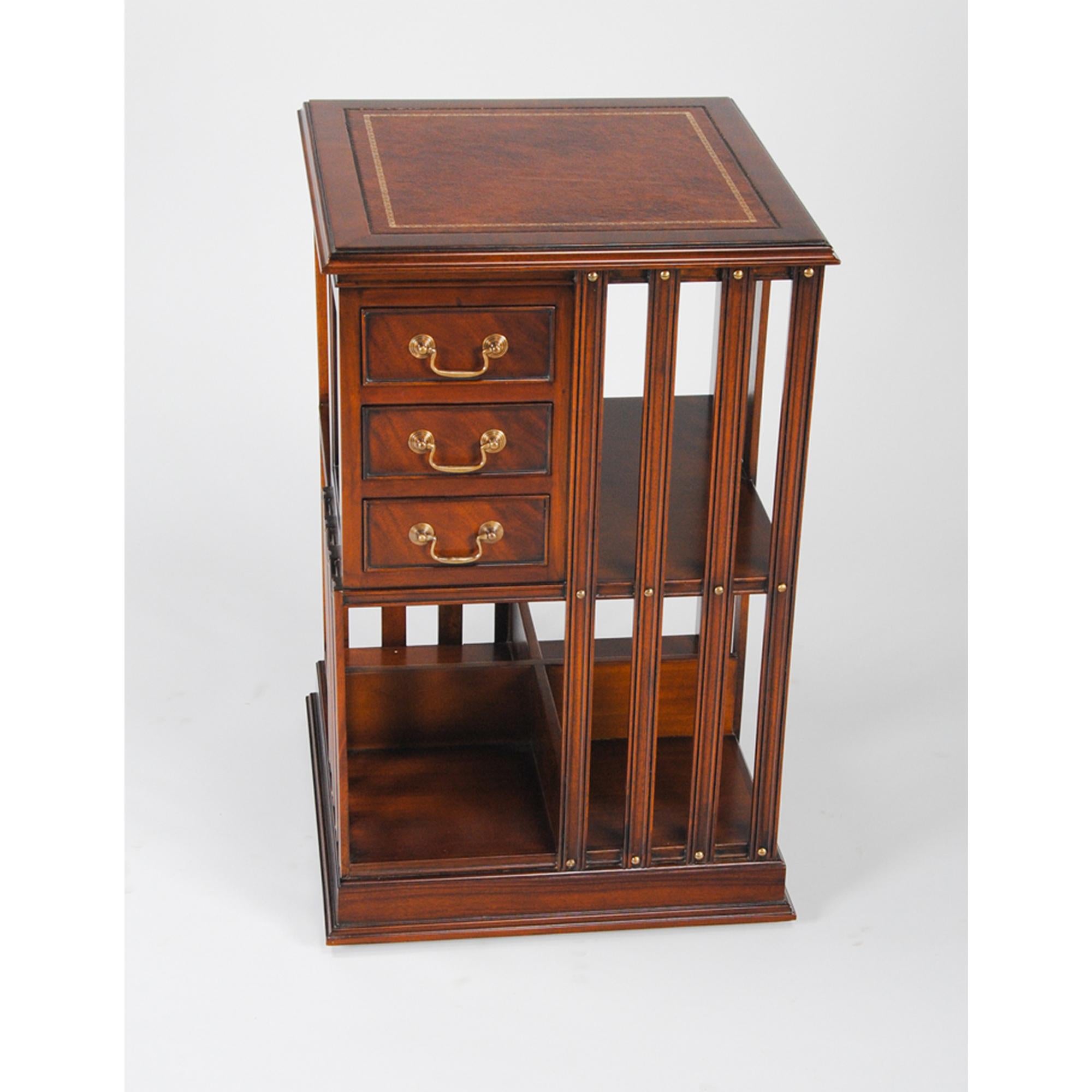 A Leather Top Revolving Bookcase from Niagara Furniture with full grain leather top with a shaped molding surround, over top three dovetailed drawers and numerous supported storage spaces, all accented with brass headed screws and hardware. The