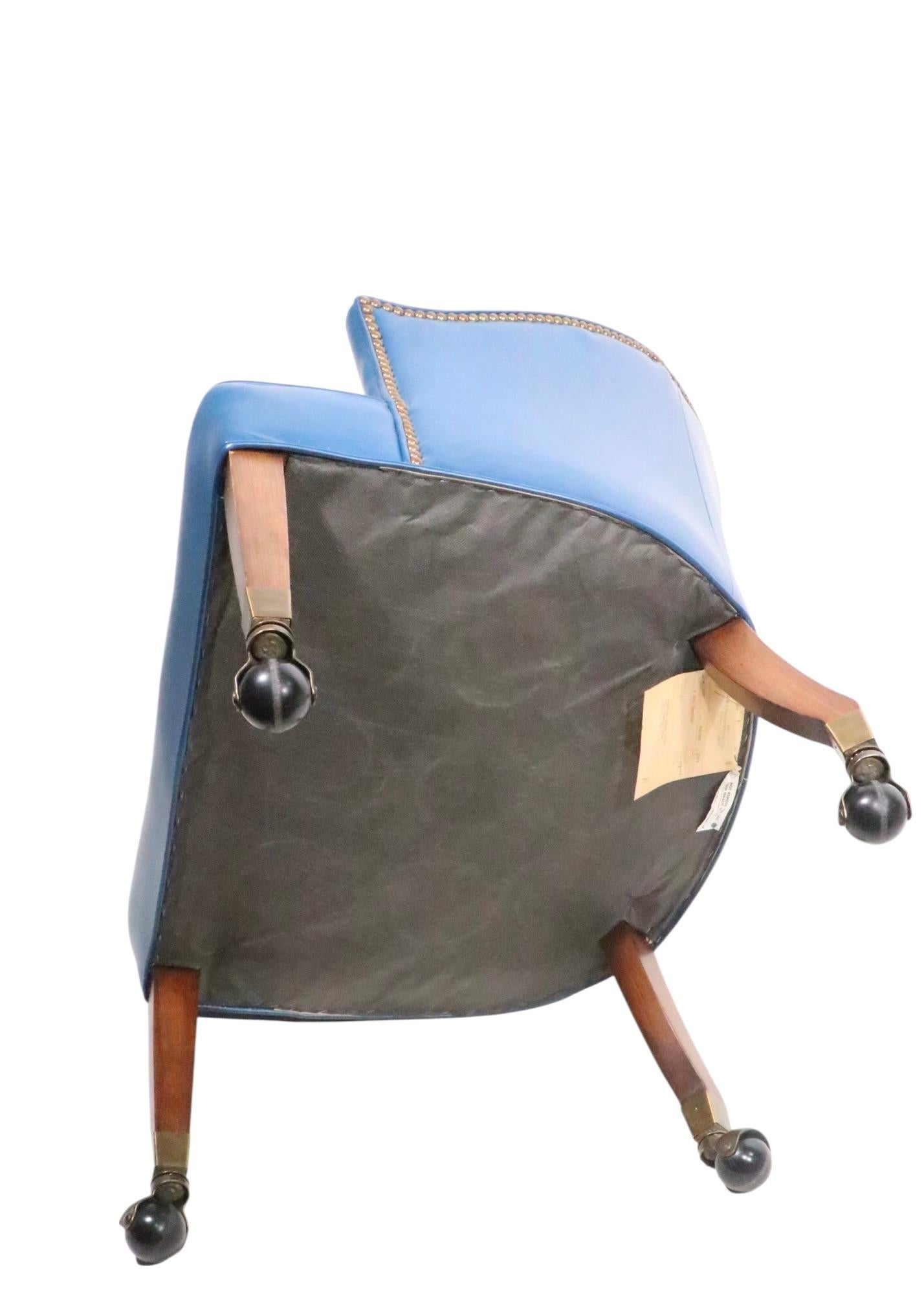 Exceptional leather tub chair in excellent original condition. This chair features chic blue leather upholstery, with brass studded nailhead trim, on solid wood legs with ball caster feet. The clean lines and restrained design make this piece