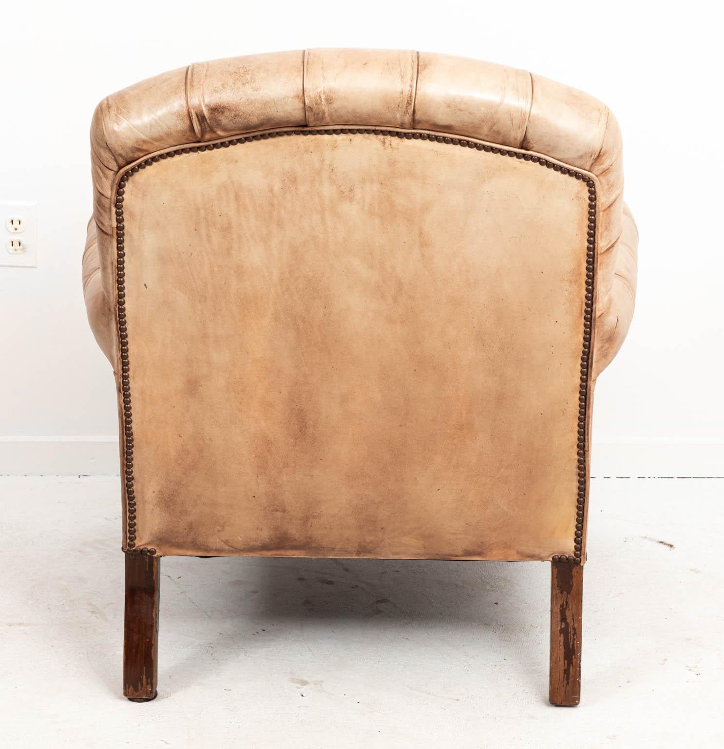 Vintage leather tufted chair with nailhead trim and exposed ring turned legs, circa 1920s. Please note of wear consistent with age including discoloration and minor finish loss to the leather. There is also evidence of chips and scratches on the