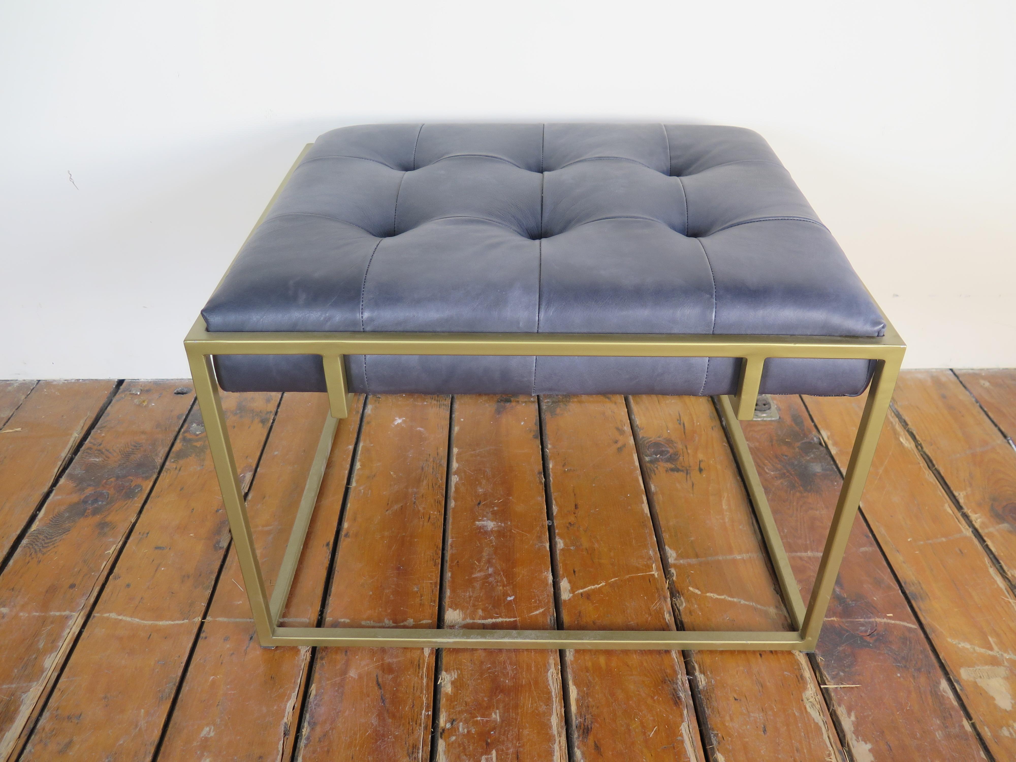 Leather tufted ottoman with gold metal legs.