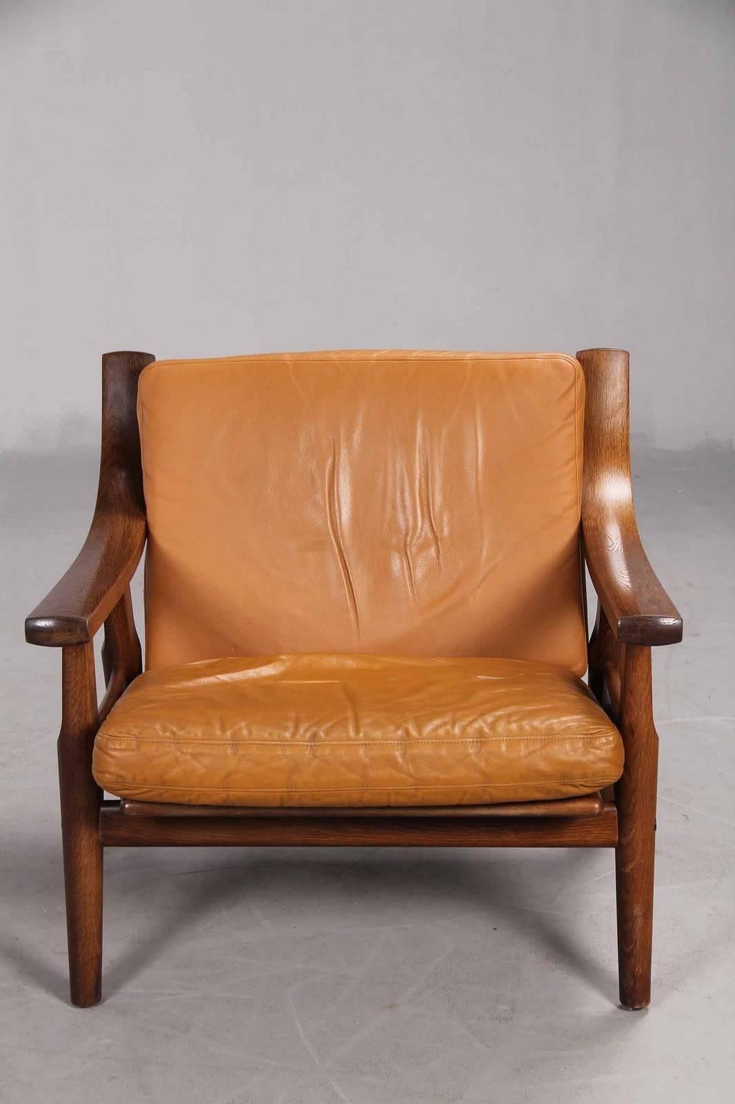Low-backed armchair designed by Danish designer Hans Wegner in 1973. The frame of dark-stained oak with spoke back. The chair upholstered in cognac-colored leather. The chair produced by GETAMA, model-GE-530.
