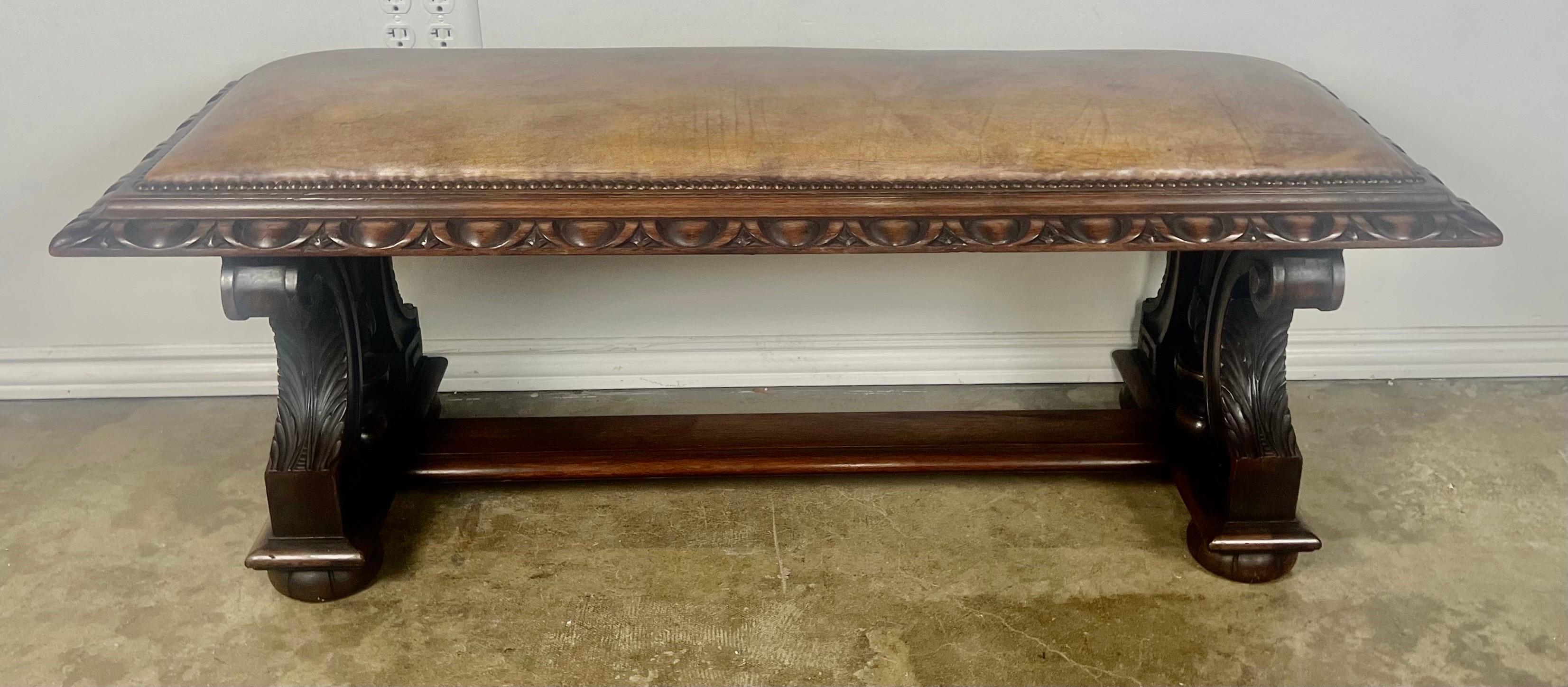 19th C. English Tutor style walnut bench with egg/dart detail.  The bench stands on four bun feet.  The handsome bench is covered in a rich leather with antique nailhead trim detail.