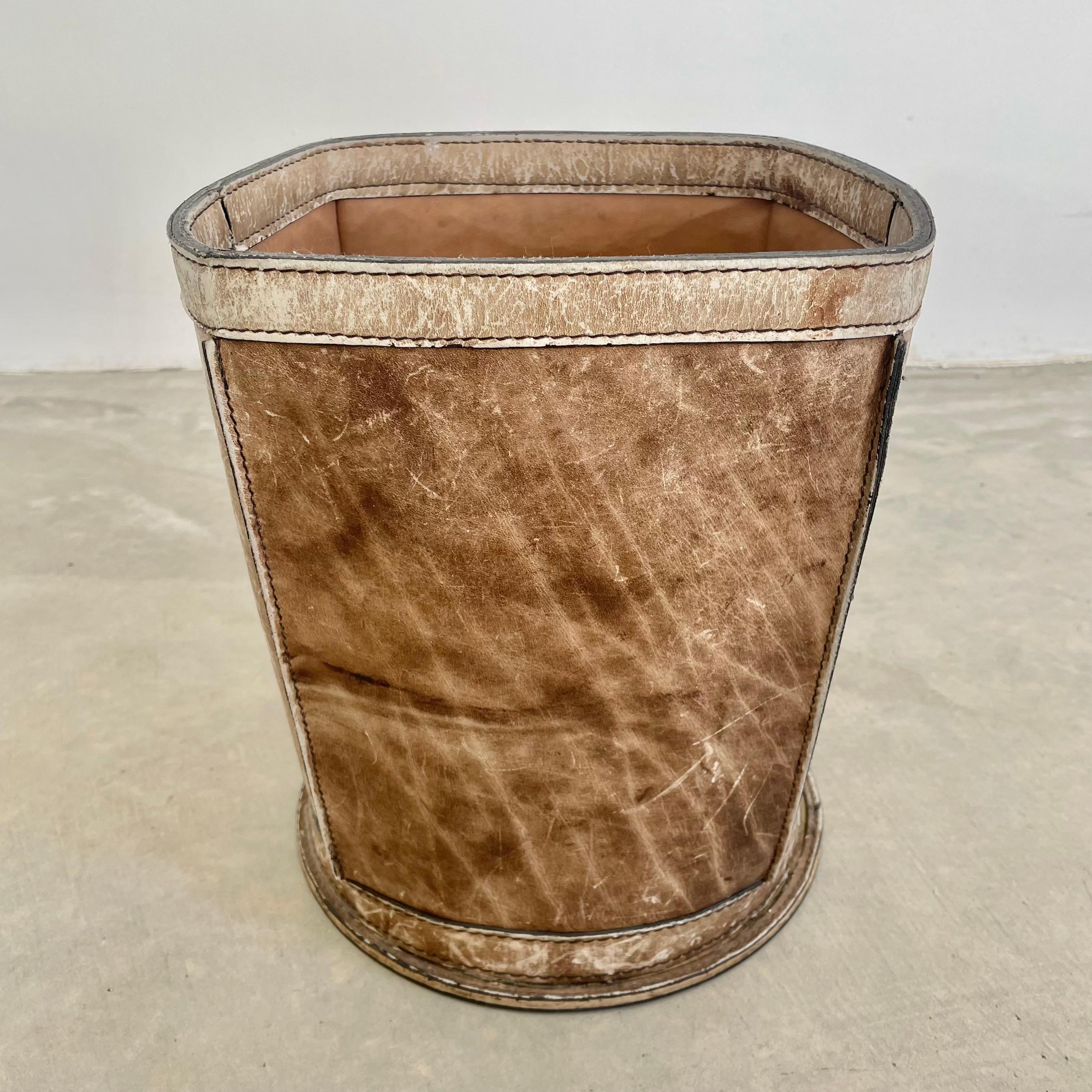 Beautiful distressed leather waste bin. Fully made of a thick cowhide leather with the upper stitched in a square shape and fastened onto a circular base giving it great lines. Great army brown color with deep brown undertones. High quality leather