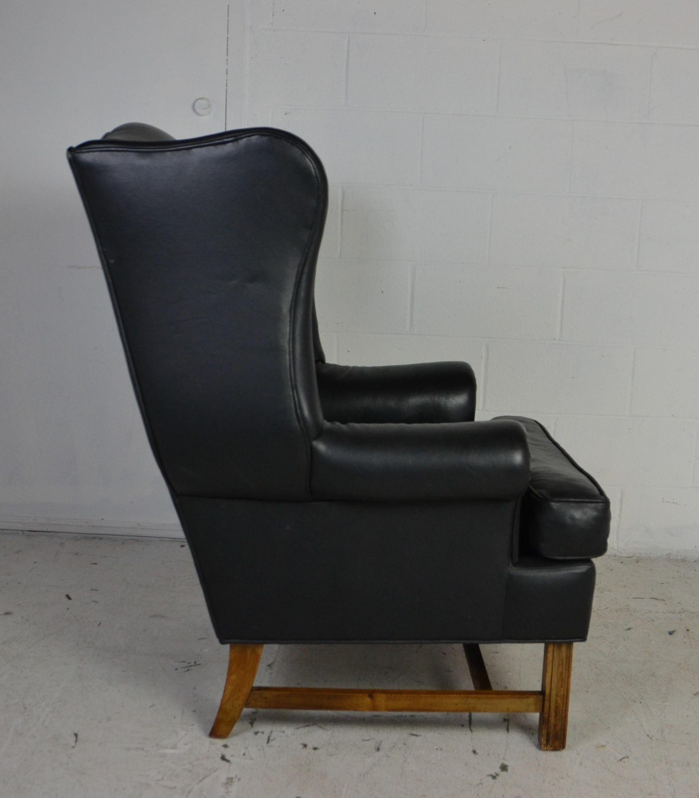 A good quality wingback chair in the traditional style. Upholstered in black leather and sitting on Marlborough style, reeded straight legs.