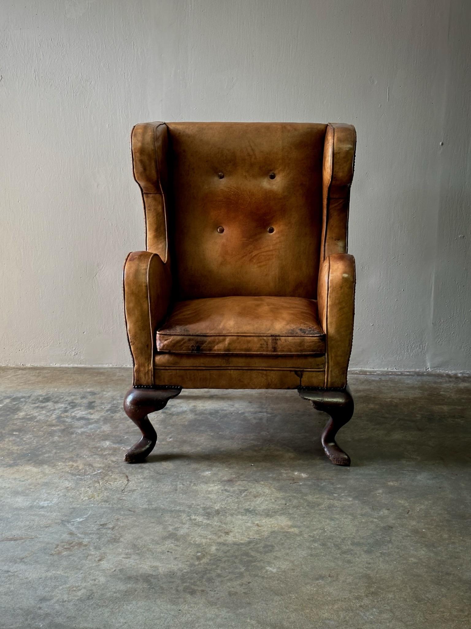 French late 19th century wingback armchair with original chestnut leather upholstery and carved wooden feet. Features a uniquely linear silhouette and exquisite patina. Bold yet understated. 

France, circa 1890

Dimensions: 30.7W x 29.5D x 44H (SH