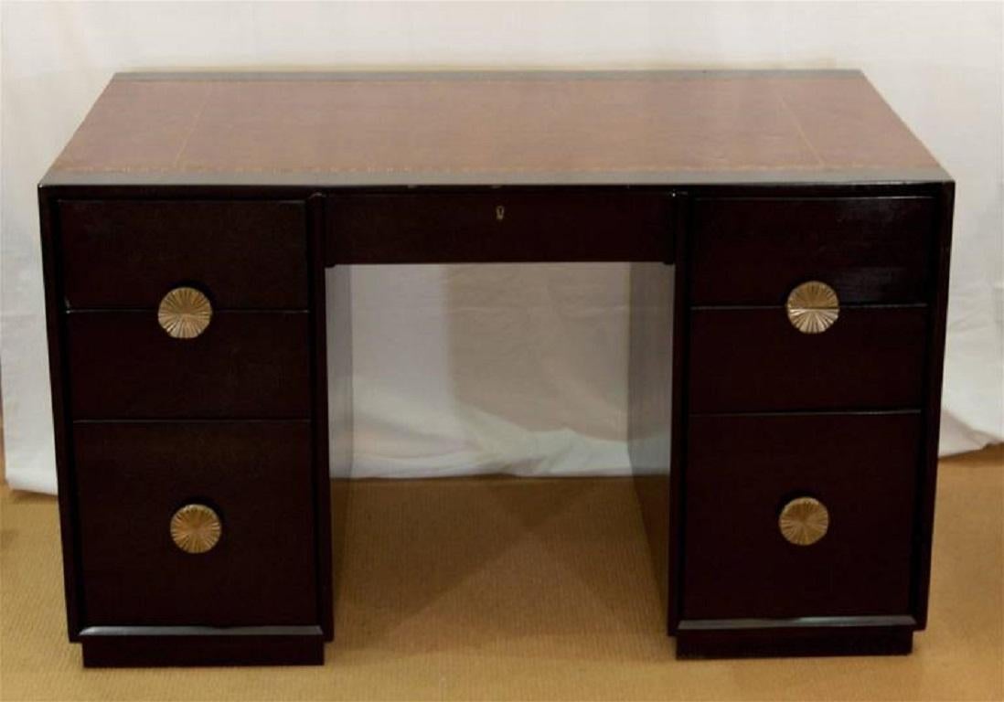 Midcentury ebonized desk by Charak Modern with camel colored leather top and embossed Greek key detailing, attributed to Tommy Parzinger. Each of the six drawers have substantially sized sunburst brass pulls. Finished on all sides, obverse of desk