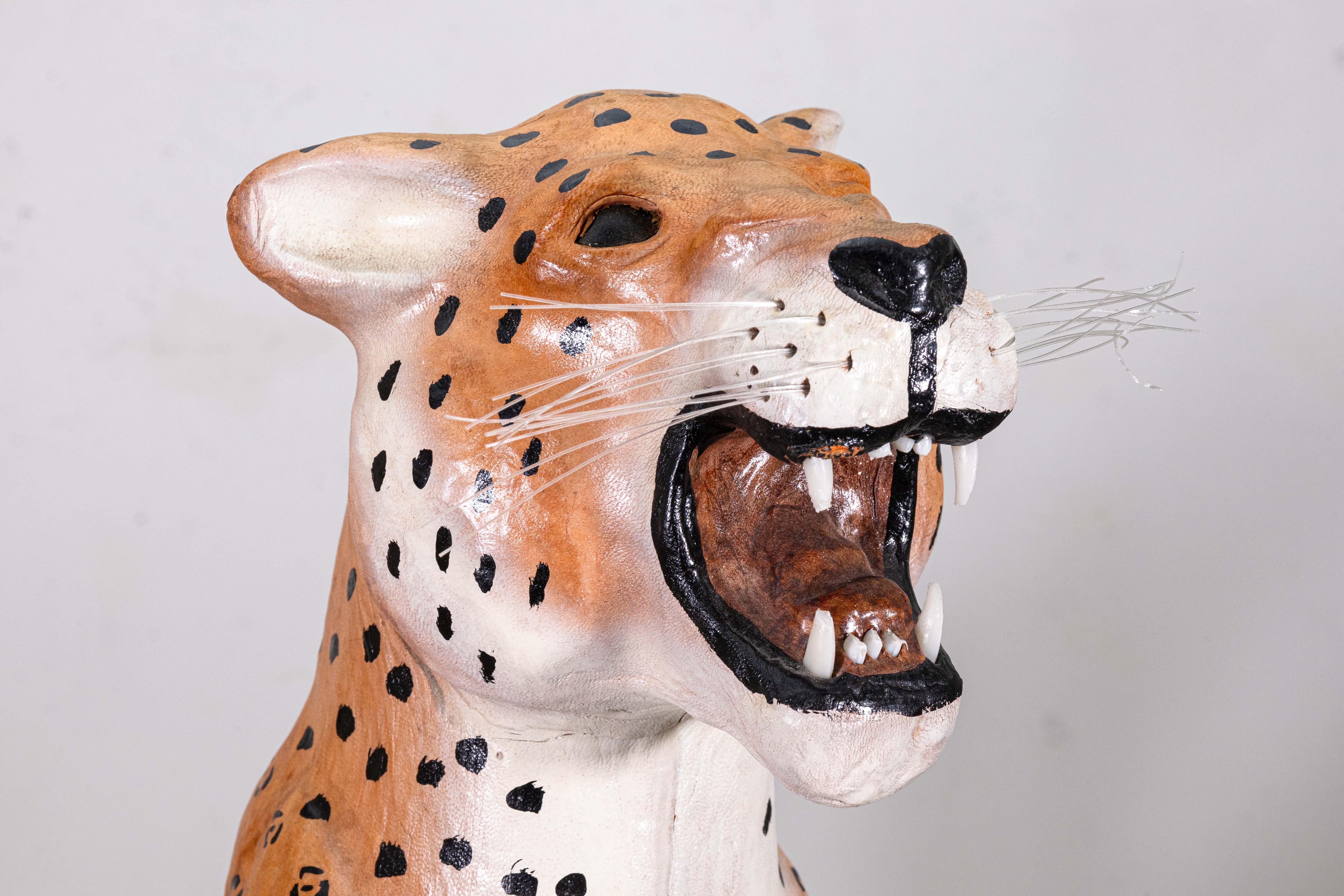Una scultura di ghepardo avvolta in pelle realizzata a mano. Questa graziosa scultura di animali raffigura un ghepardo ridimensionato, ma simile alla vita, in posizione seduta e ruggente. Questo pezzo è avvolto in una pelle che conferisce alla
