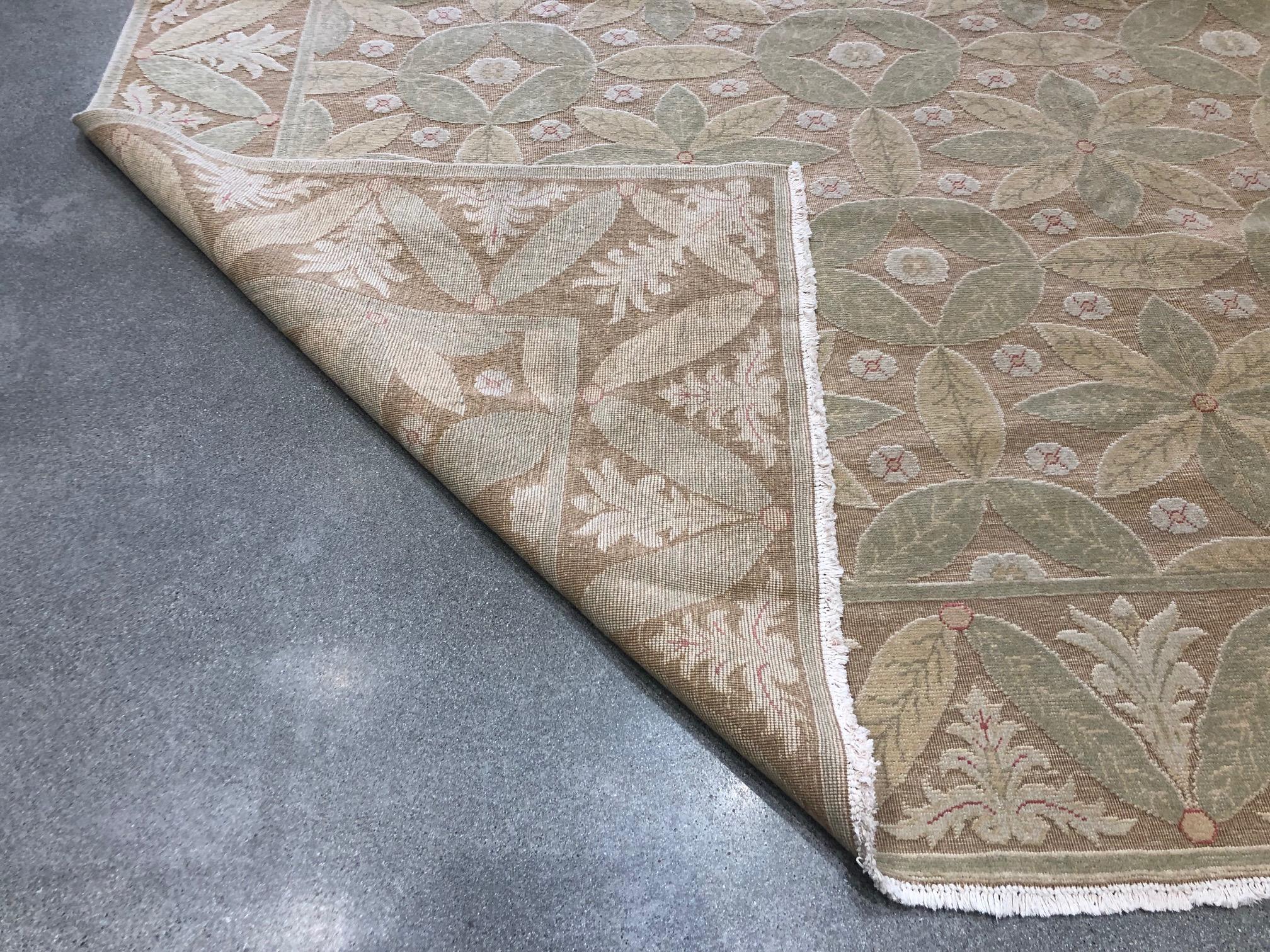 Leaves of green and yellow have been artfully arranged to give a lightly tropical feel to a durable wool area rug. Small cream blossoms burst from the spaces in between to add to the multi-dimensional look. Handmade in Europe.