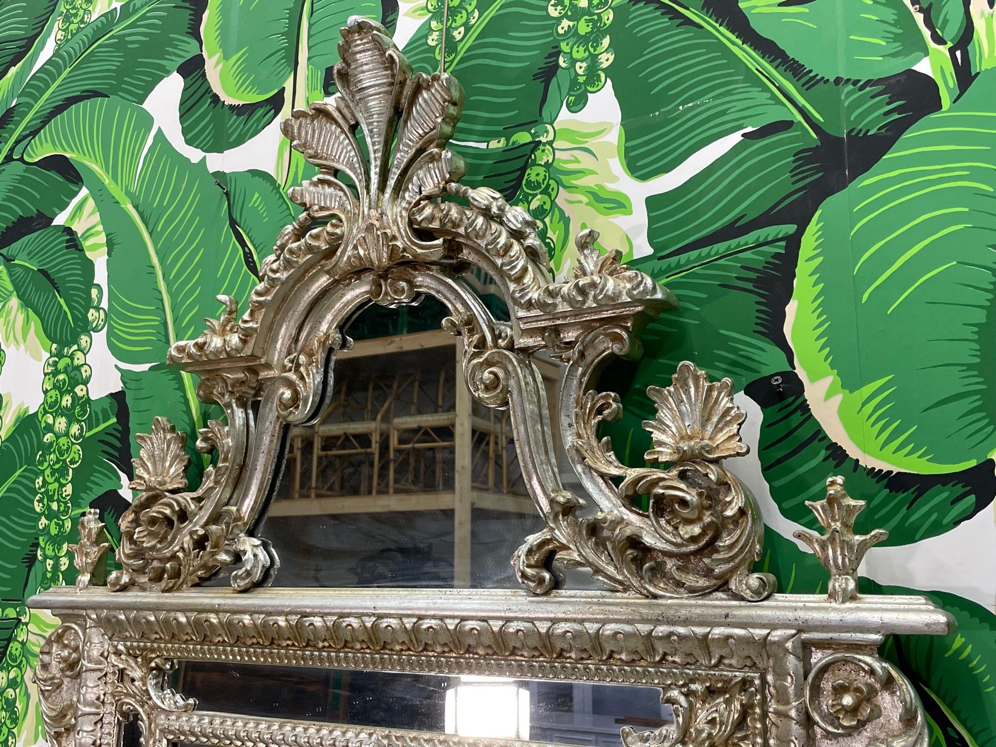 Monumental giltwood mirror by LaBarge features a hand carved double frame in a mottled silver leaf finish. A spectacular crown sits atop a head plinth with scrolled acanthus leaves and other foliate elements accented with palmettes and flowers. The