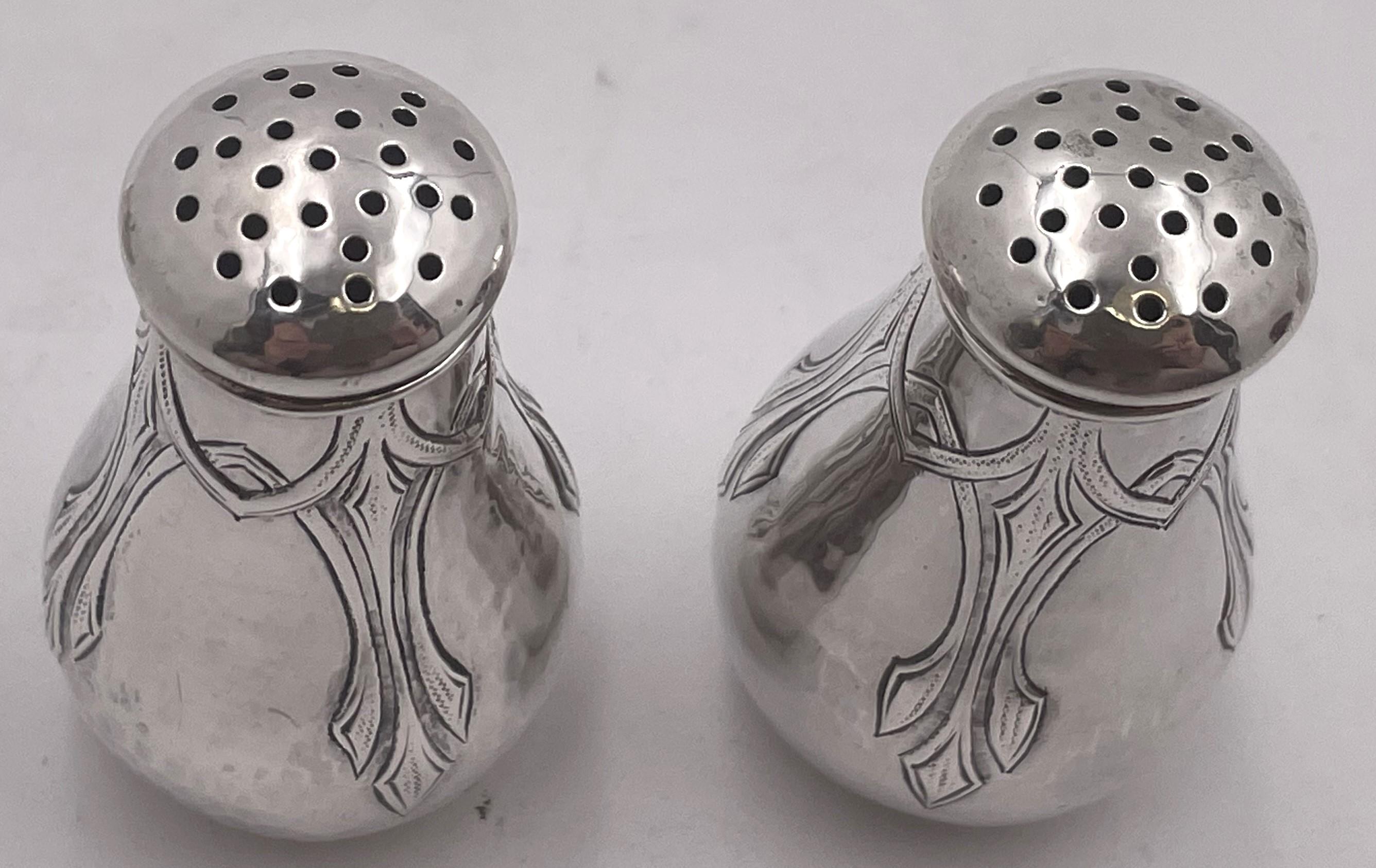 Pair of Lebolt 
Co. sterling silver salt and pepper shakers in Arts 
Crafts style, beautifully handmade and hand-hammered, adorned with elegant, geometric motifs, from the early 20th century. They measure 2 1/2'' in height by 1 1/2'' in