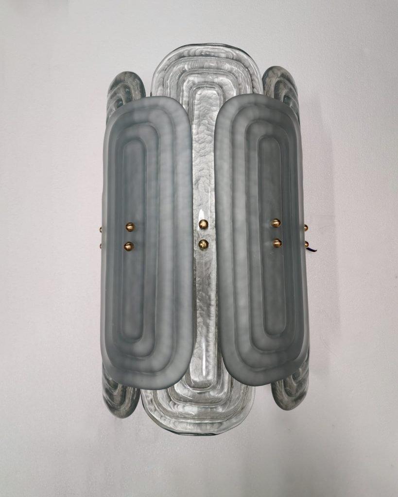 Apliques de Murano italianos fabricados por eModerno, creados meticulosamente en Italia para cumplir los más altos estándares de calidad.
Con dos tamaños distintos de cristal rectangular firmemente sujetos a un marco semicircular adornado con