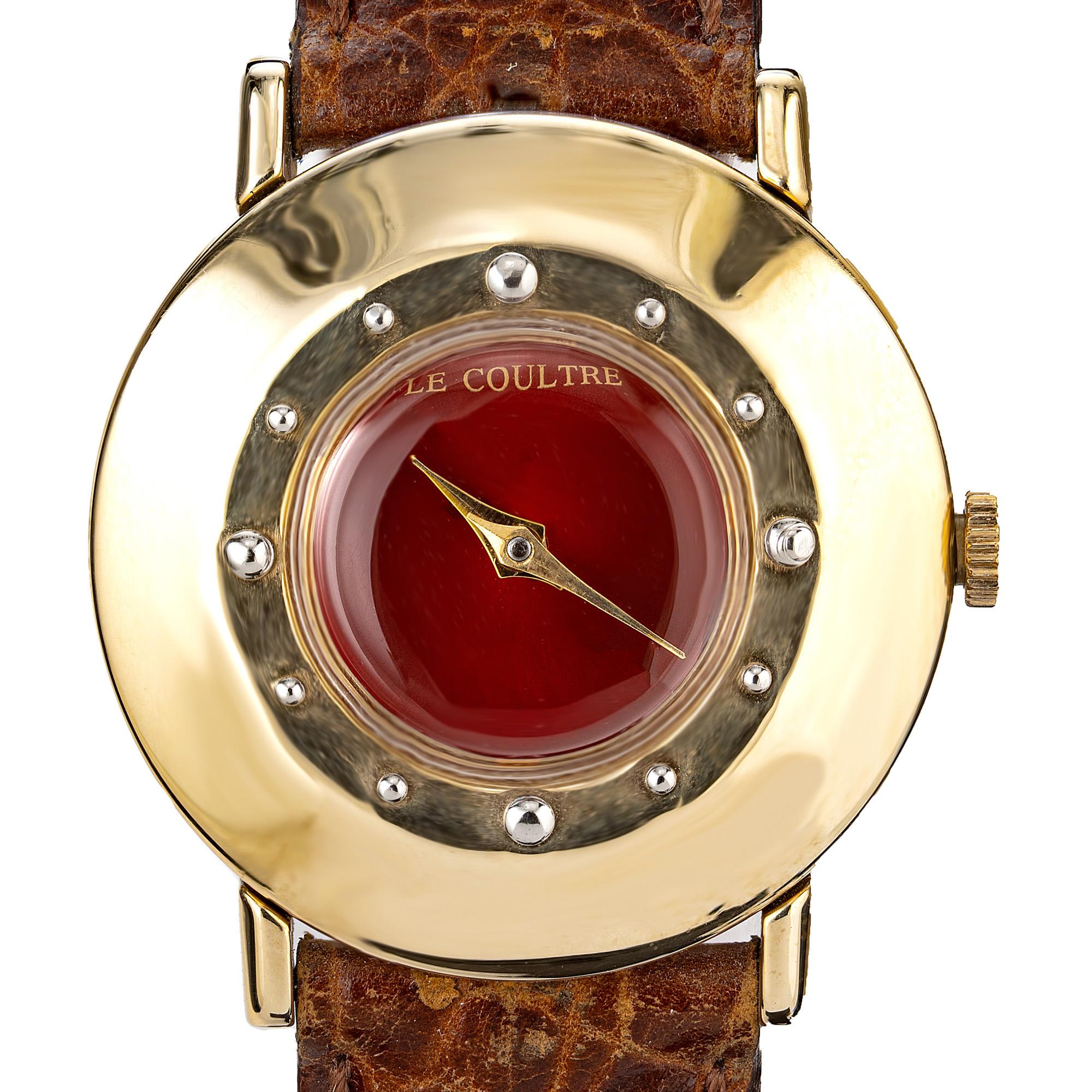 Diese exquisite LeCoultre-Damenarmbanduhr aus Gelbgold aus der Mitte des 19. Jahrhunderts ist ein wahres Meisterwerk an Eleganz und zeitlosem Charme. 14k Gelbgold rundes Gehäuse mit einem schlichten roten Zifferblatt. Das strahlende Gelbgoldgehäuse