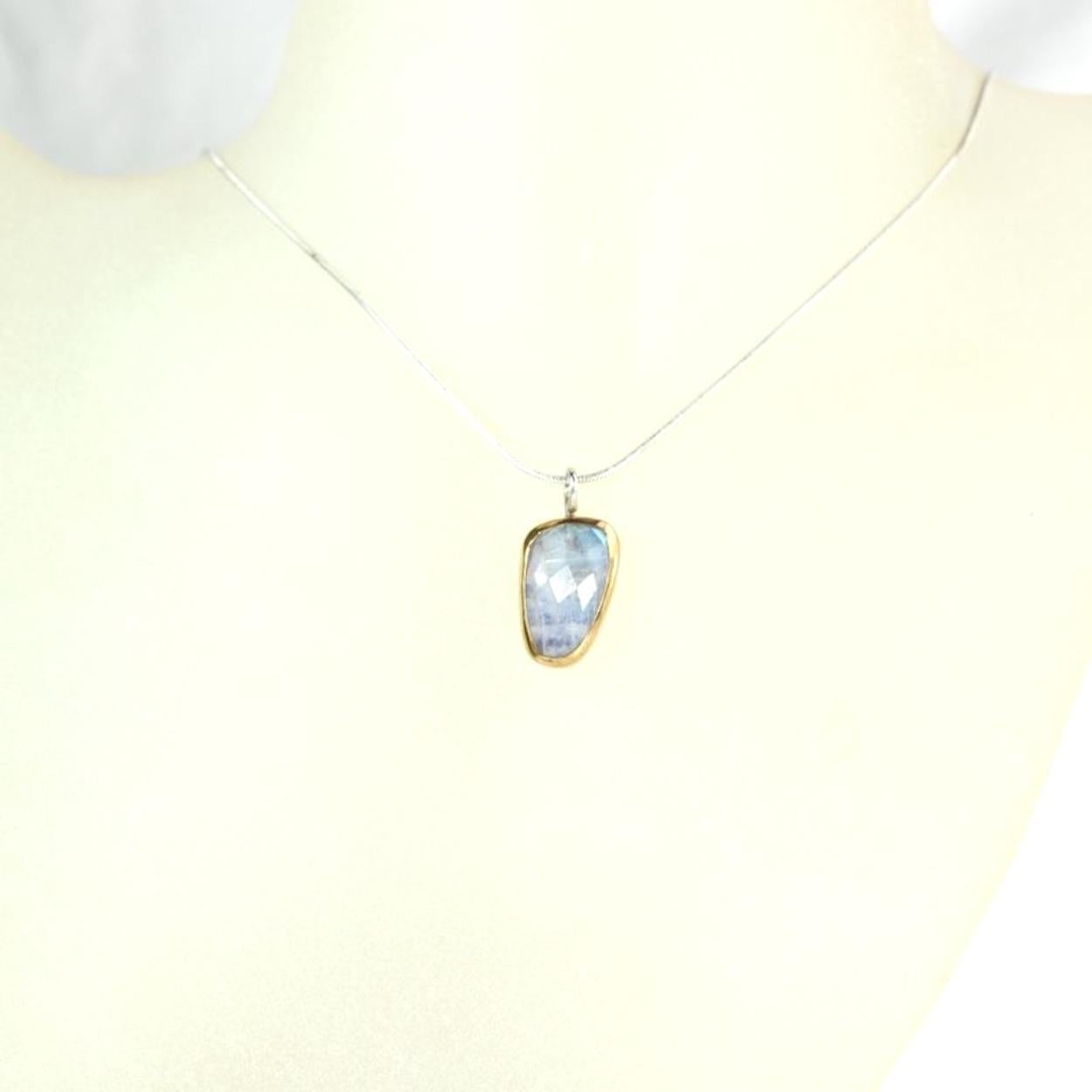Rose cut rainbow moonstone pendant, handset in a 22K gold bezel with a solid sterling silver back. The back of the bezel plate is oxidized to give this stone a moody, mysterious glow. Sterling silver wirework. This pendant includes a 18″ sterling