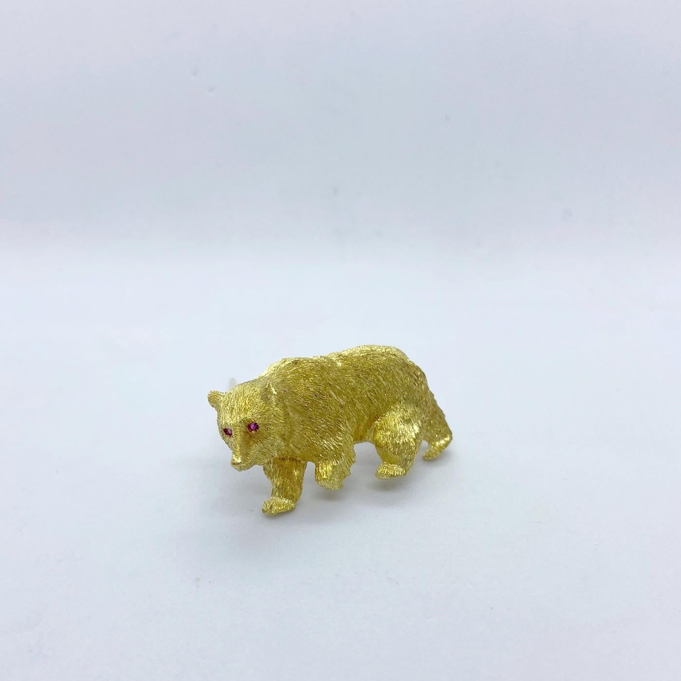 An 18 karat yellow gold bear brooch with an etched and sandblasted finish that gives us the appearance of the bear's fur. He is accented with ruby eyes. 1.75