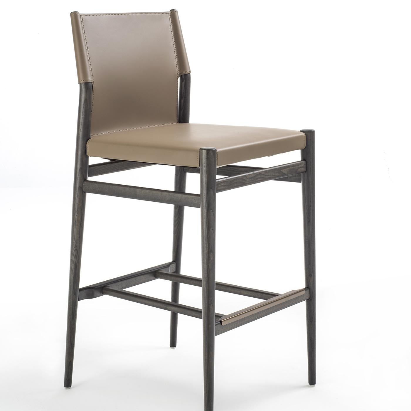 This gray-ash wooden bar stool is covered in taupe-colored leather and features a footrest with painted steel protector. Its solid, yet minimal, silhouette and combination of substantial, natural materials recalls the hallmarks of Scandinavian