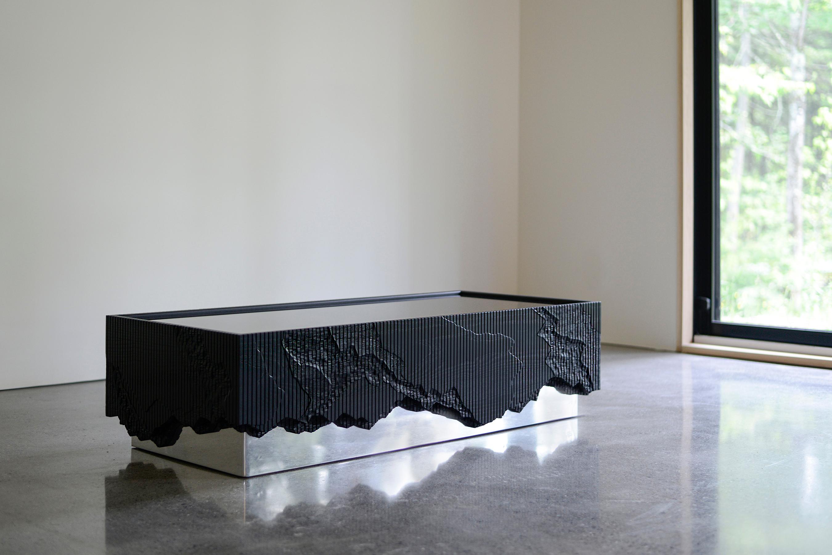 Ledge Coffee Table, is made of solid ash with a black glass top and a mirror polished base. It stems from material exploration inspired by cliffs around the studio, making solid ash reference crumbling stone through layered hand carving. 
The Shale