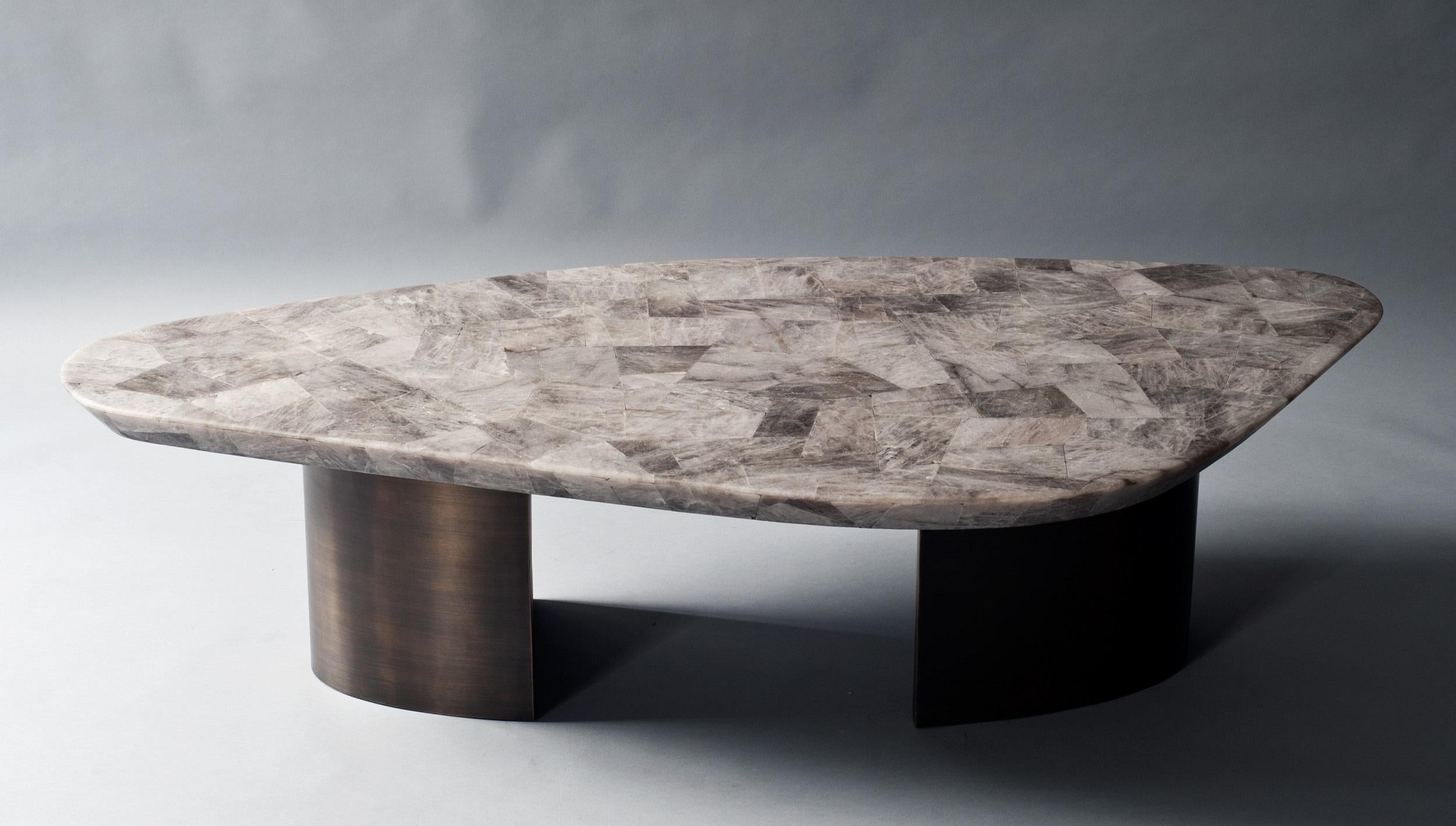 The ledge nested coffee or cocktail tables have sculptural tops in leathered Smokey Quartz supported by an antique brass base. The tables can be purchased individually or as a pair as shown.