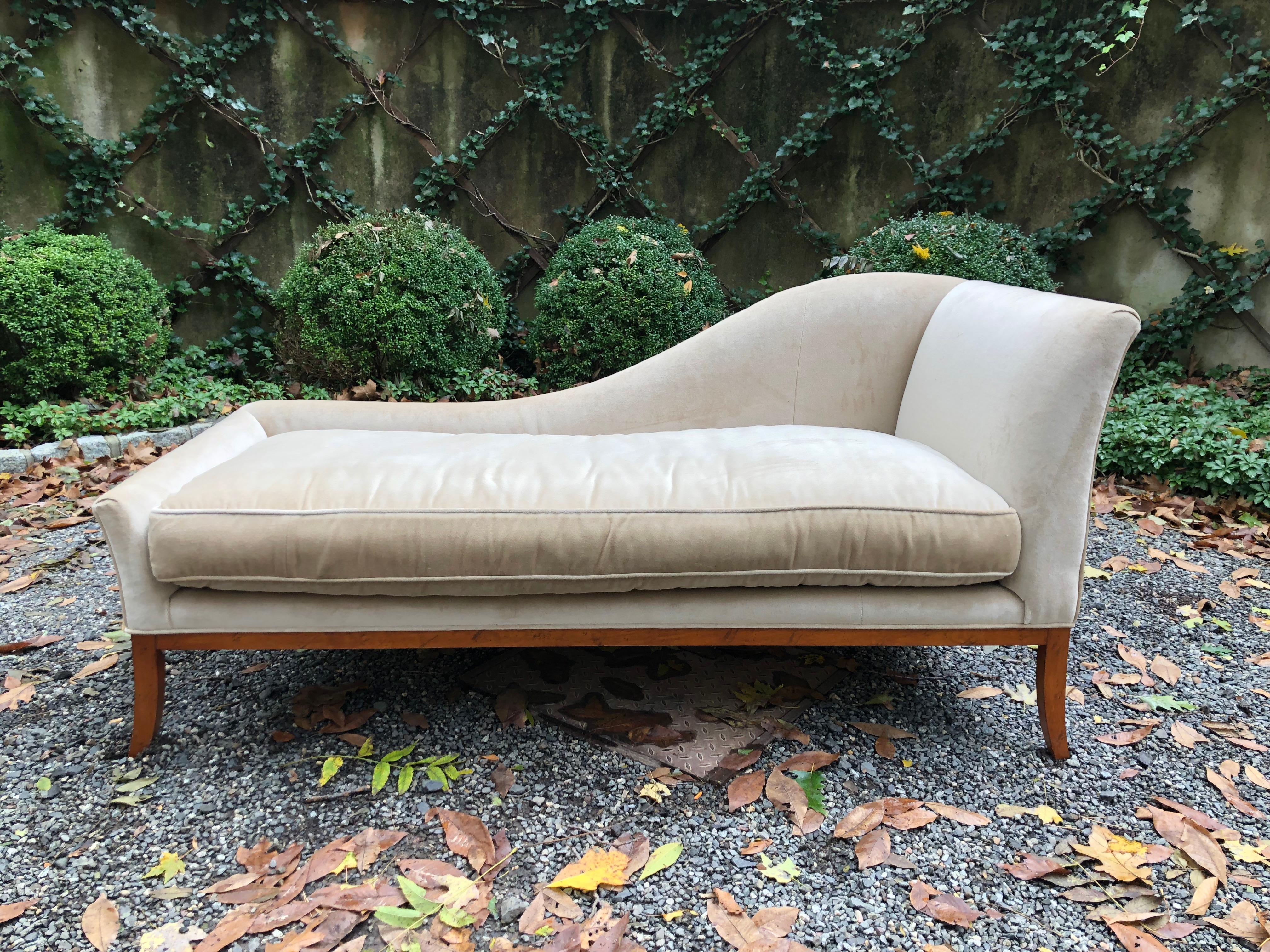 Sophisticated champagne velvet chaise lounge by Lee Jofa, having a delicate sloping arm and slightly splayed legs. The wooden frame has a beautiful pecan wood finish. Loose cushion is down filled. 

Seat arm heights are 21 (low end) and 35 (high