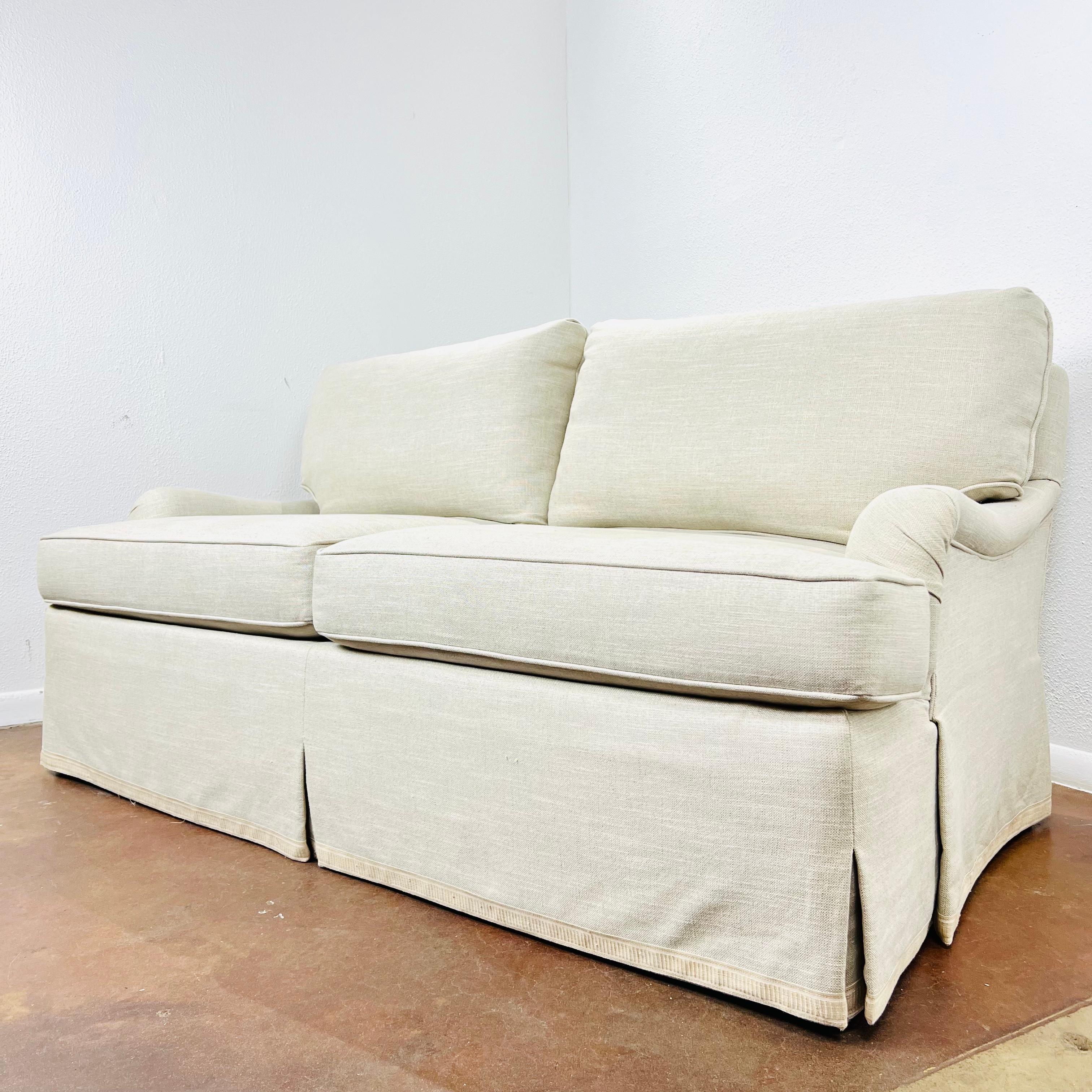 This elegant English-arm loveseat by Lee Jofa features feather down wrapped T cushions, down filled loose back cushions, and tapered legs under a waterfall skirt. Upholstered in Lee Jofa linen fabric. Very good condition with no rips, tears, or