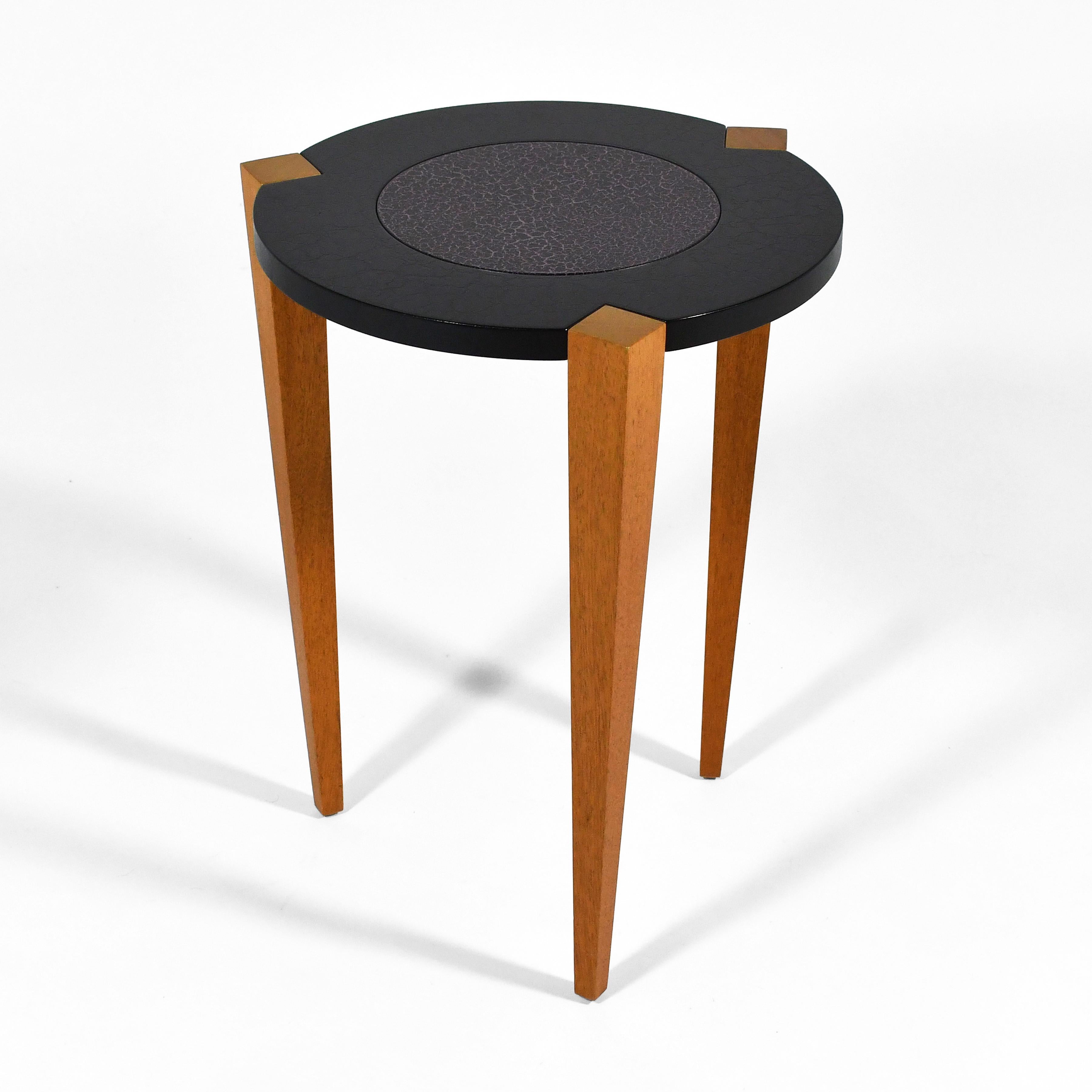 A playful post-modern design, this side table by Lee Weitzman is reductive in form, but also embraces surface decoration with the black and plumb crackled paint finish. The round top is supported by three tapered maple legs. Hand signed and dated on