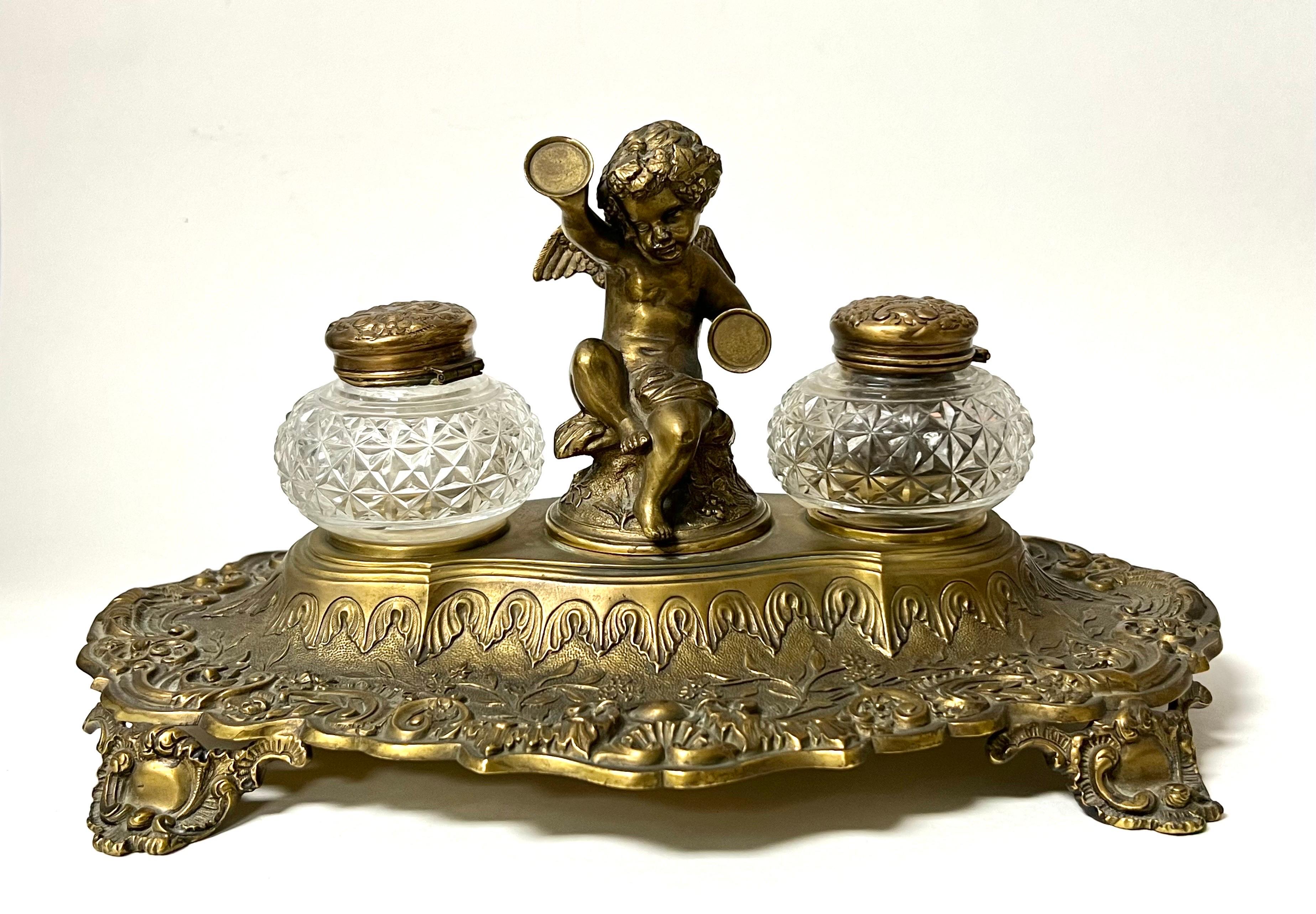 Inkwell with cherub and crystal wells. Brass, most likely originally silver plated. In great condition otherwise. Quite decorative and collectible.