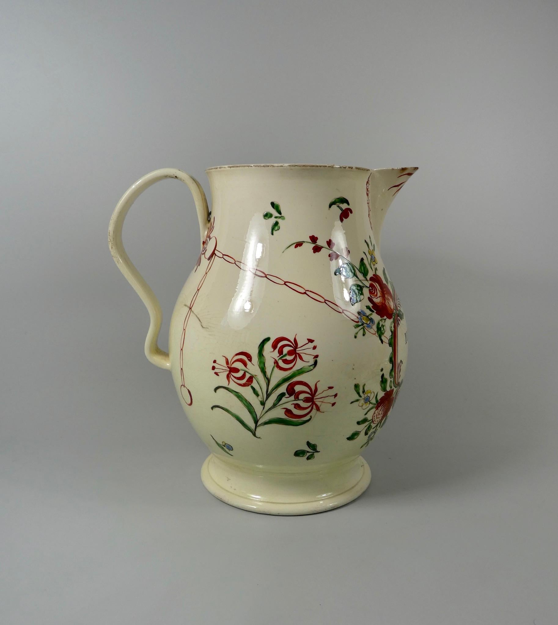 A fine and large Leeds creamware jug, dated 1773. Probably painted at the David Rhodes workshop, with an oval scrollwork panel, inscribed ‘John Pickford, 1773’, beneath the spout, which is painted in iron red, with scrollwork. The panel is suspended