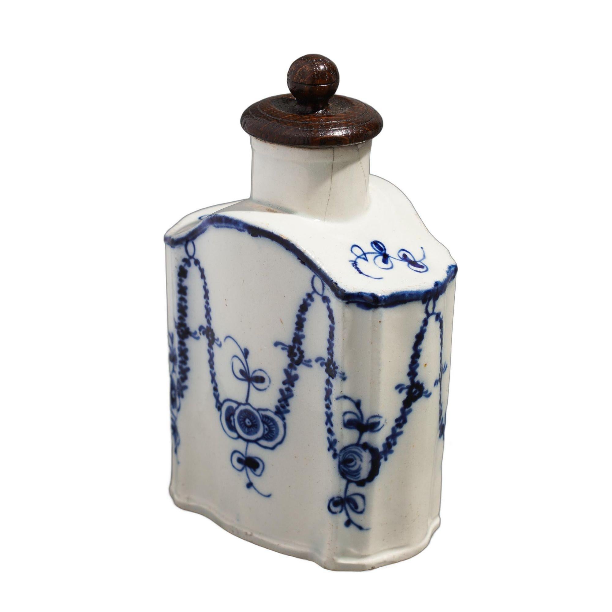 Antique Bombay shaped English pearlware tea caddy with a distinctive decoration in blue cobalt. The caddy is hand decorated with flower pendants draped from rings painted from a continuous line which traces the edges of the shoulder of the caddy