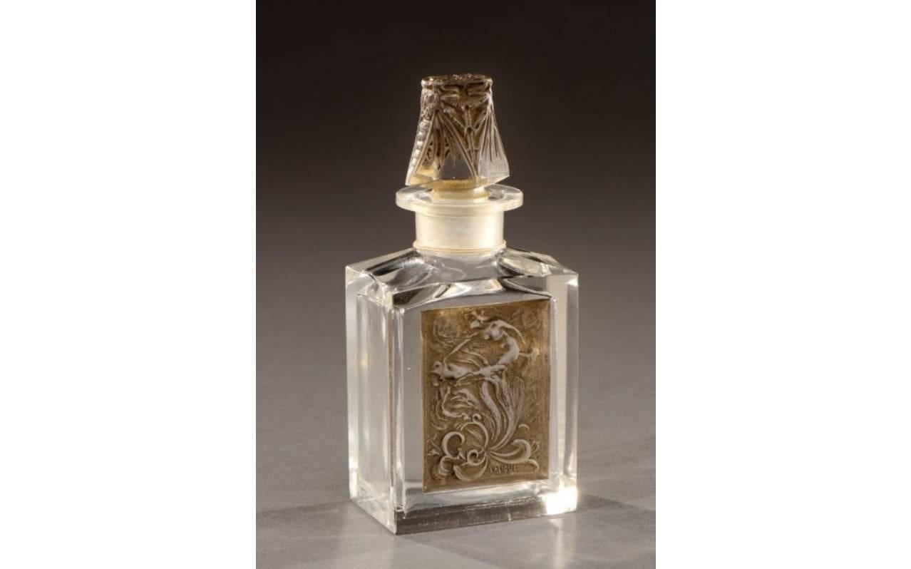 “L'effleurt”, moulded-pressed, transparent and black patina perfume bottle.
model created in 1912 Signed “Lalique”.
With decor in reserve of a figurine emerging from a flower, with their caps appearing two cicadas confronted. Model produce 1912.