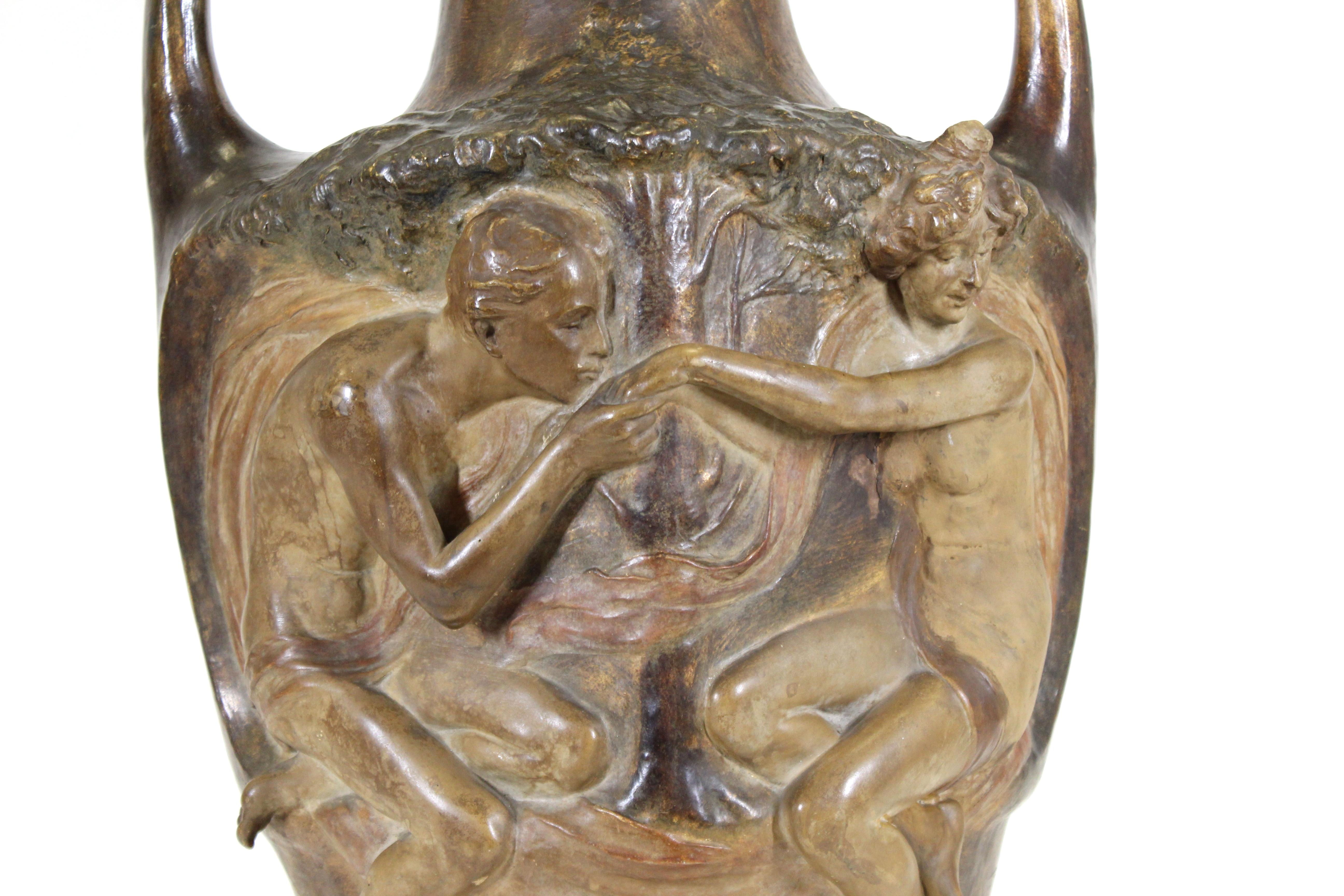 Viennese Art Nouveau large exhibition vase by Lefont for Friedrich Goldscheider. The piece depicts a bas relief of a young couple on one side and putti frolicking in a forest on the back side. Signed Lefont on the side and stamped by Goldscheider.