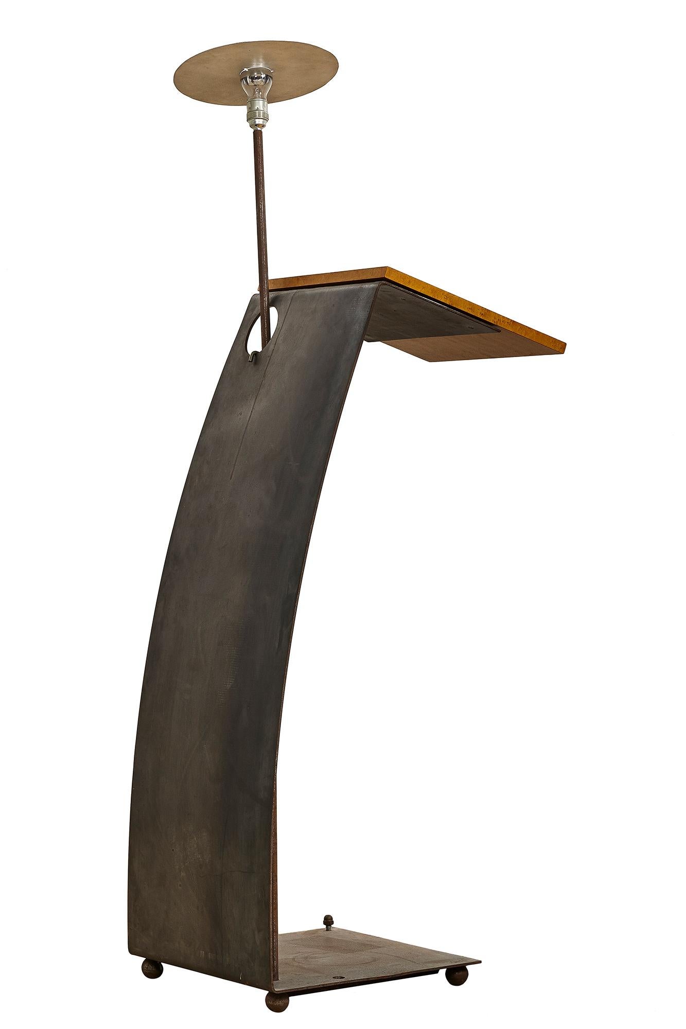 Pupitre Magratiga produit par Poltronova en 1990. Sa structure courbe en tôle brute supporte une étagère en bois d'où émerge un luminaire à tige. Le présent objet est un prototype 0, ce qui en fait un spécimen unique et non reproductible. Son design