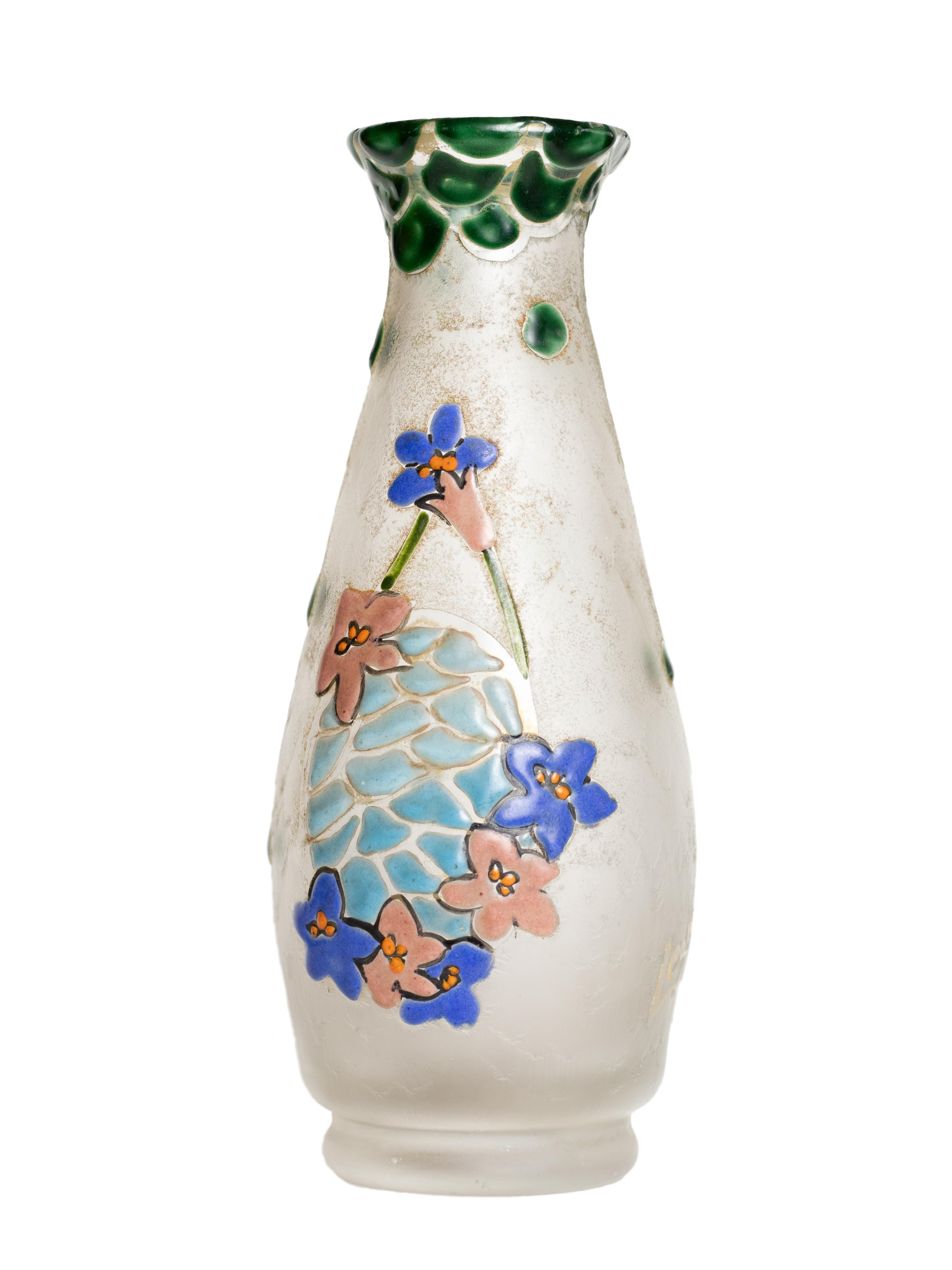 Eine Glasvase mit weißem Hintergrund und rosa und blauen Blumen und grünen Blättern, die in Säure geätzt sind.
