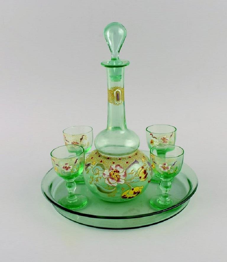 Legras, Frankreich. Cabarat Cigogne Likör in grünem mundgeblasenem Kunstglas mit handgemalten Blumen. 
Ca. 1900.
Bestehend aus einer Karaffe, einem Serviertablett und vier Gläsern.
Die Karaffe misst: 23,5 x 10 cm.
Die Gläser messen 7,5 x 4,5