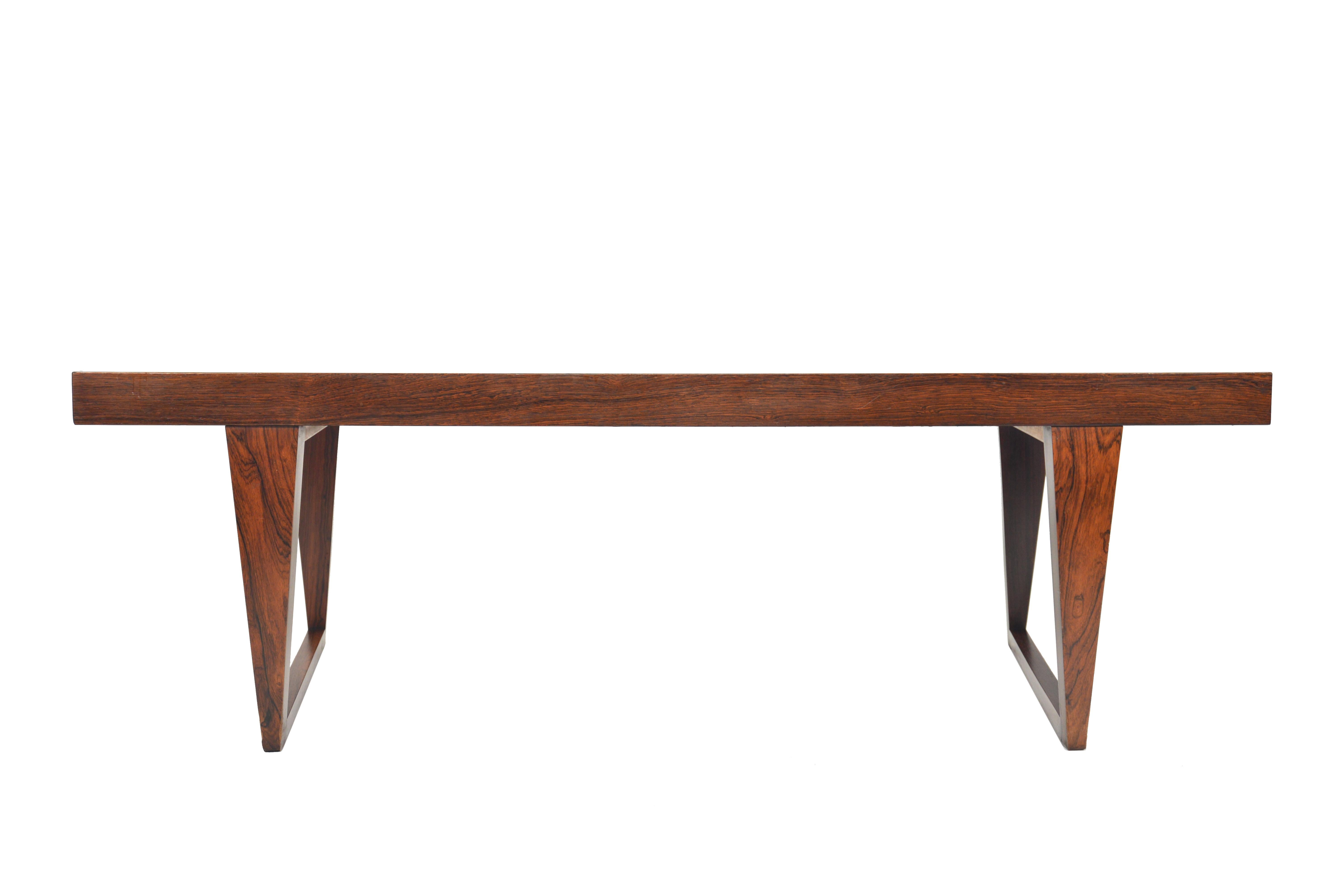 This Danish modern midcentury coffee table in rosewood was designed by Leif Hansen for the ‘Geisha’ collection. Expertly built, this gorgeous piece features a sweeping curve rosewood tabletop and stands on a sleigh base. In excellent original