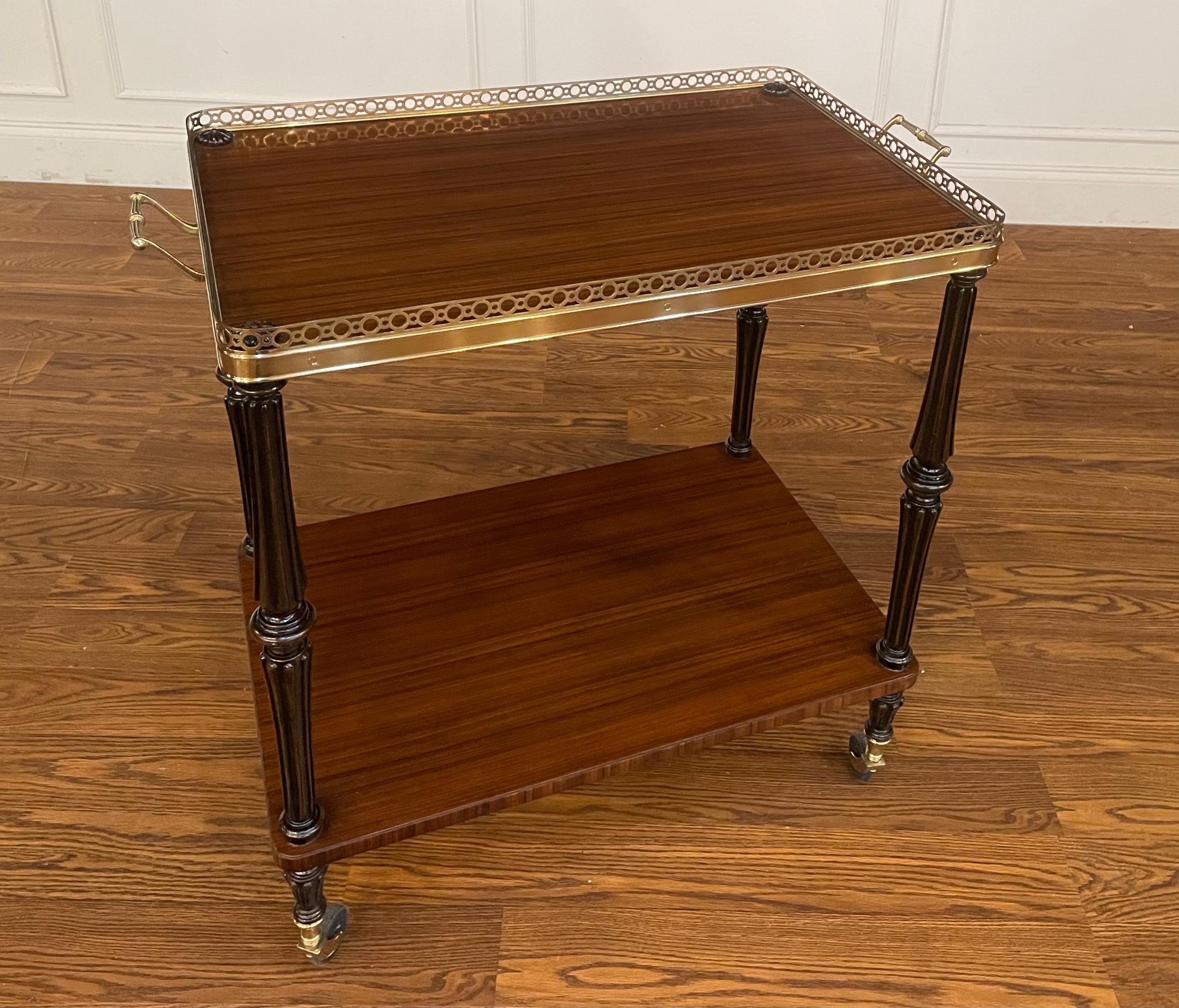 This is a serving cart/trolley by Leighton Hall Furniture.  It features ebonized posts with exotic Pau Ferro wood for the shelves, brass accents and casters for easy movement.  It was used as a showroom sample for approximately one year and is in