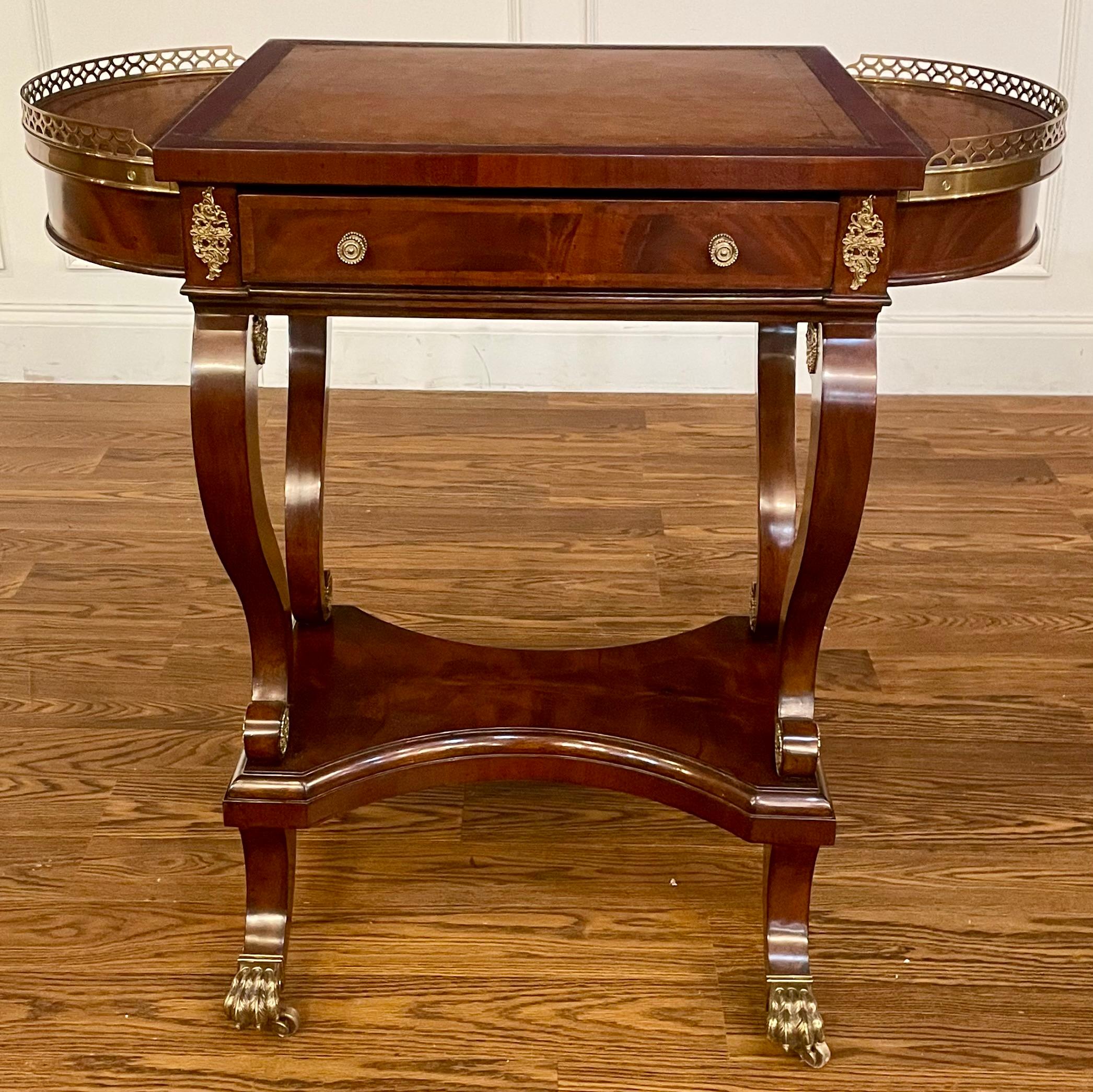 This is a unique mahogany game/occasional  table by Leighton Hall.  It is a showroom sample. It is less than one year old and in very good condition. It features a mildly distressed leather top with edge tooling, two fold up side compartments for