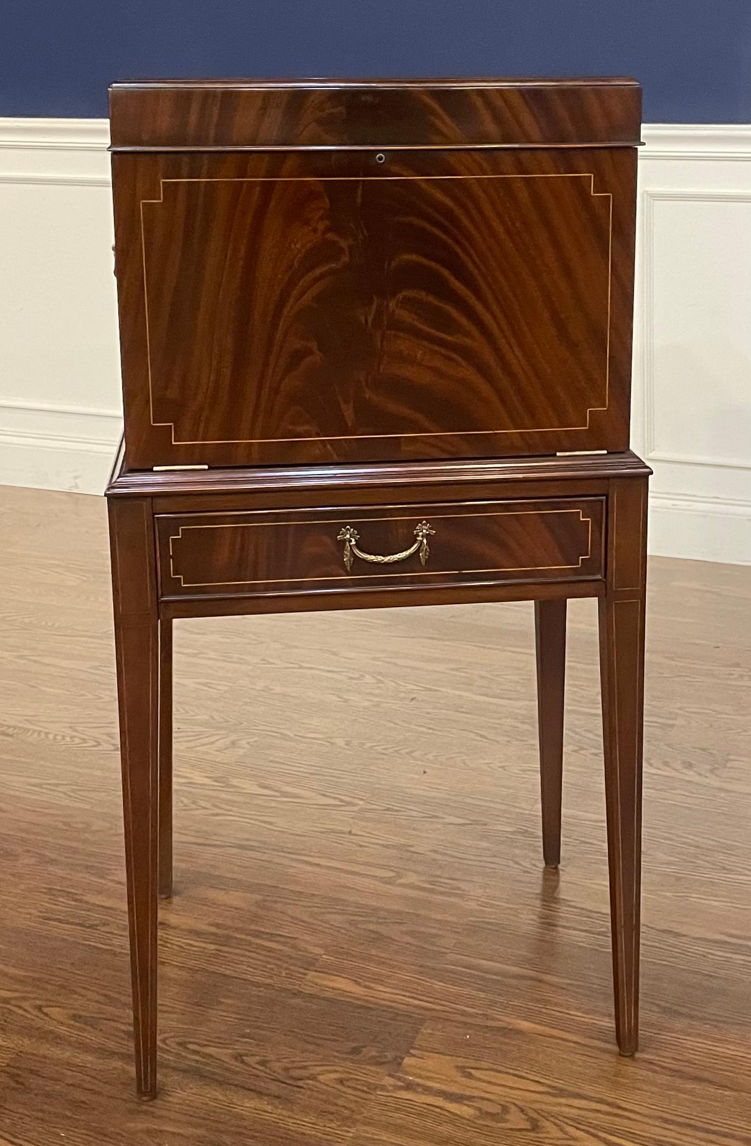 This is a traditional mahogany silverware chest by Leighton Hall.  It features swirly crotch mahogany with inlays and classic Hepplewhite style square tapered legs.  There are four drawers and a top tray for silverware.  There are silverware inserts