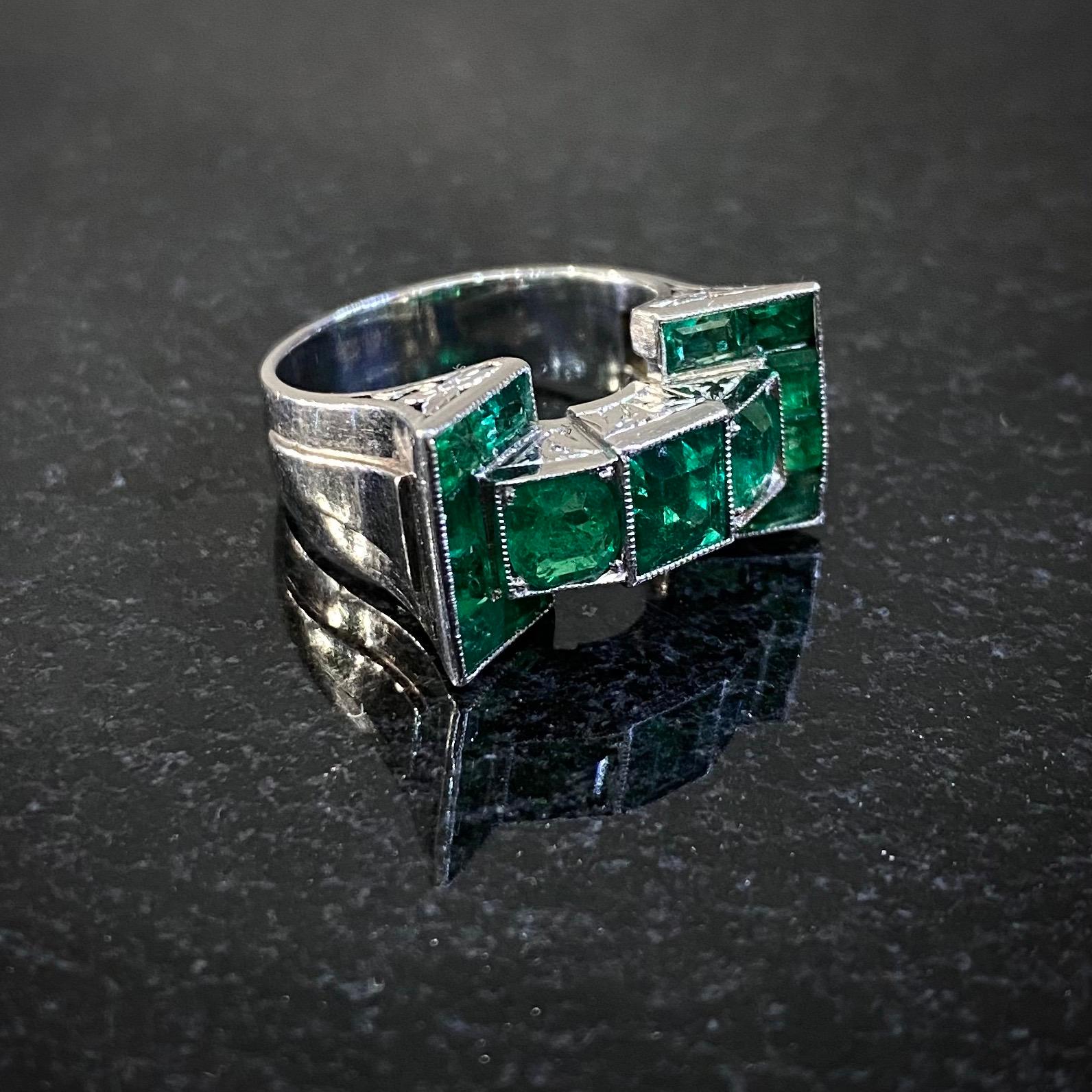 Leitão & Irmão Art Deco Colombian emerald geometric Odeonesque cocktail ring in platinum, Portugal, circa 1930, in original maker’s case. This treasure by the Portuguese crown jeweler features 15 vivid green emeralds in open-back millegrain
