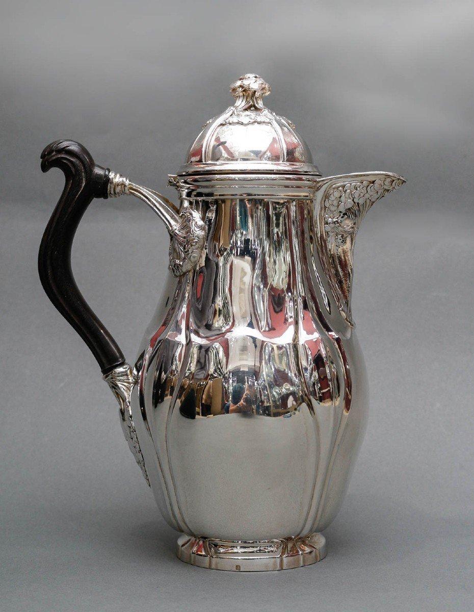 Large solid silver coffee pot with flat bottom, ovoid body, carved ebony handle, fixed with an umbel flower decoration. We find this same decoration under the pouring spout and on the hinged lid grip.

Dimensions: Height: 26 cm – width 19 cm base