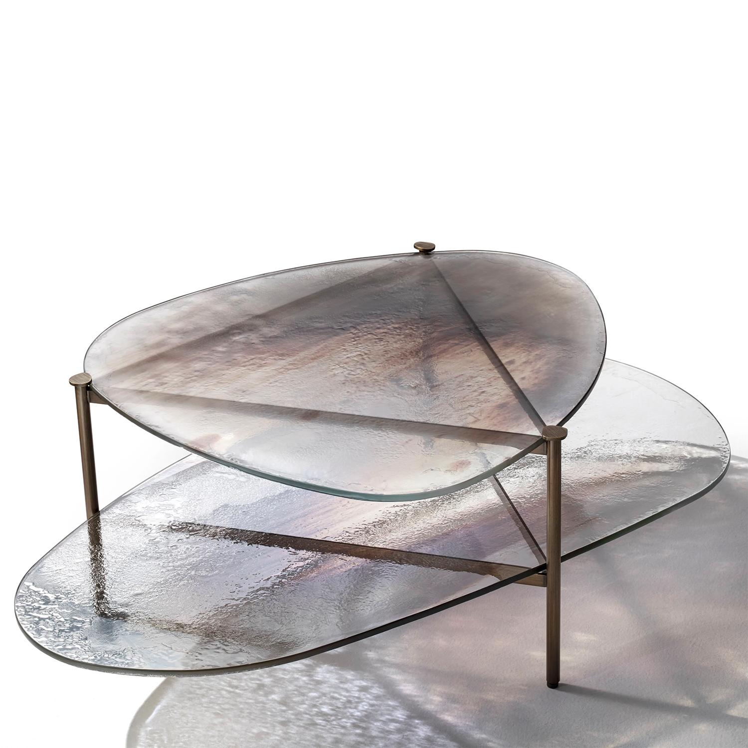 Table basse Leman avec structure en métal en finition laiton brossé
et avec haut et bas en verre, épaisseur 12 mm, avec art bronzé
et finition argentée.