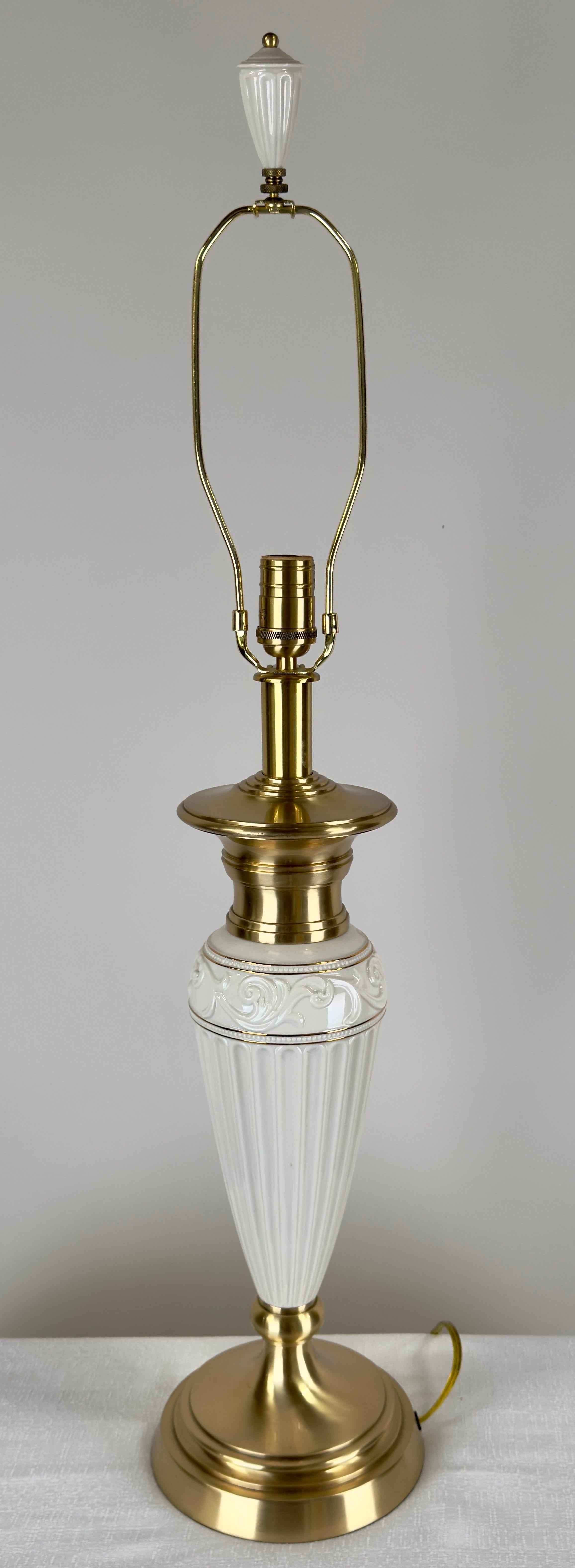 A pair of Empire style Lenox Quoizel table lamps featuring the timeless marriage of fine porcelain and polished brass.  The lamp bases feature Lenox’s signature white porcelain, finely ribbed and adorned with delicate detailing around the