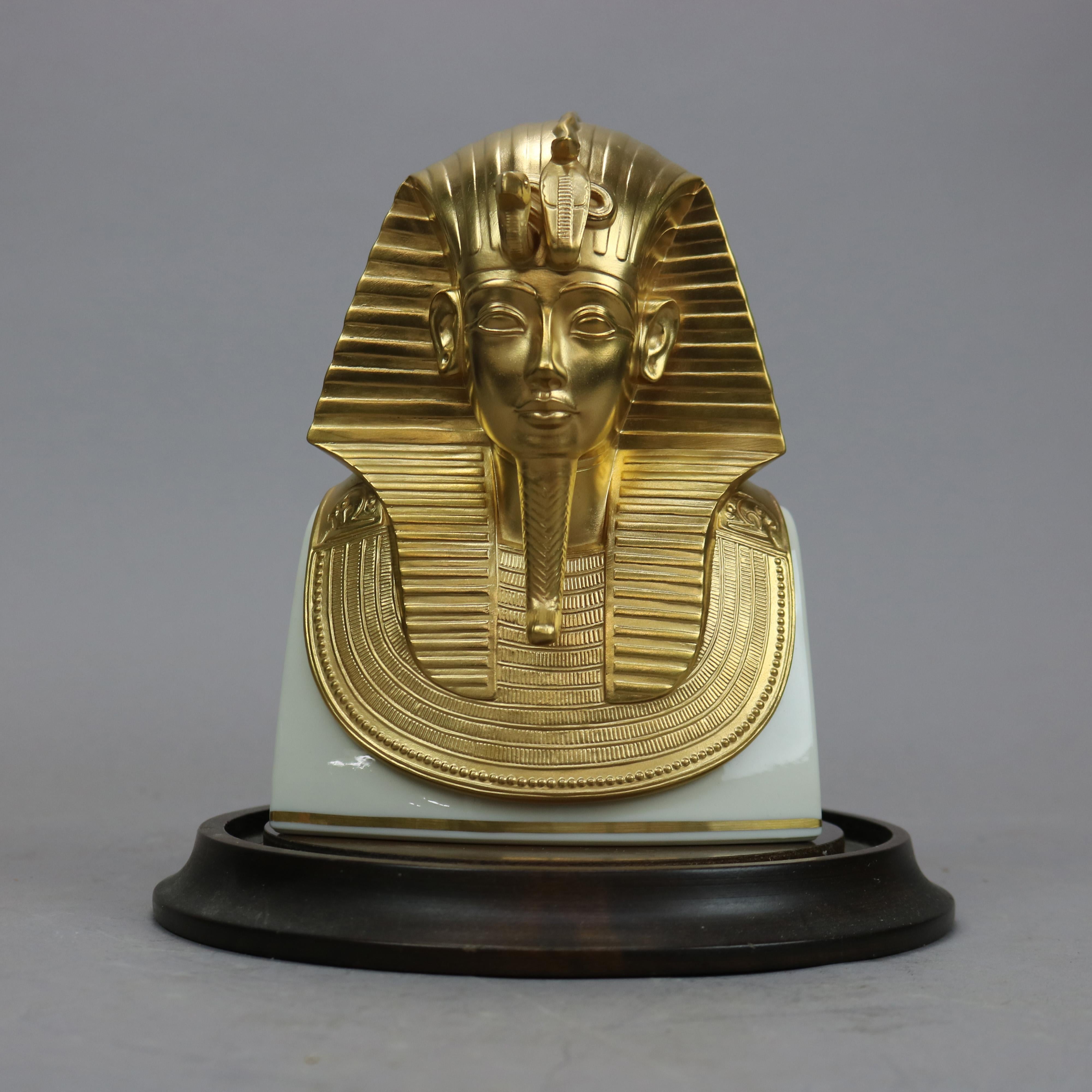 A commemorative figure by Lenox offers parcel gilt porcelain figural mask of King Tut for the Metropolitan Museum of Art, limited edition, marked on base as photographed, includes base and protective glass bell, 20th century. 

Measures- 8.75''H X