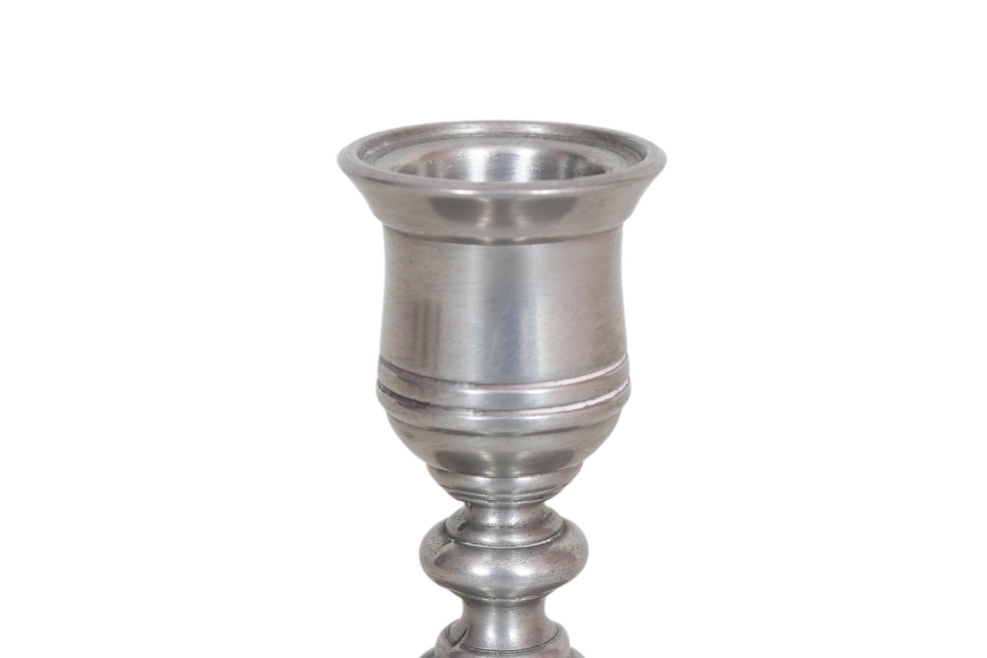 A pair of traditional pewter candlestick holders made by Lenox, circa 1990. Sleek capitals sit above round bases with a single knop, decorated with subtle beveled lines. Marked Lenox Pewter underneath. Dimensions per candle holder.