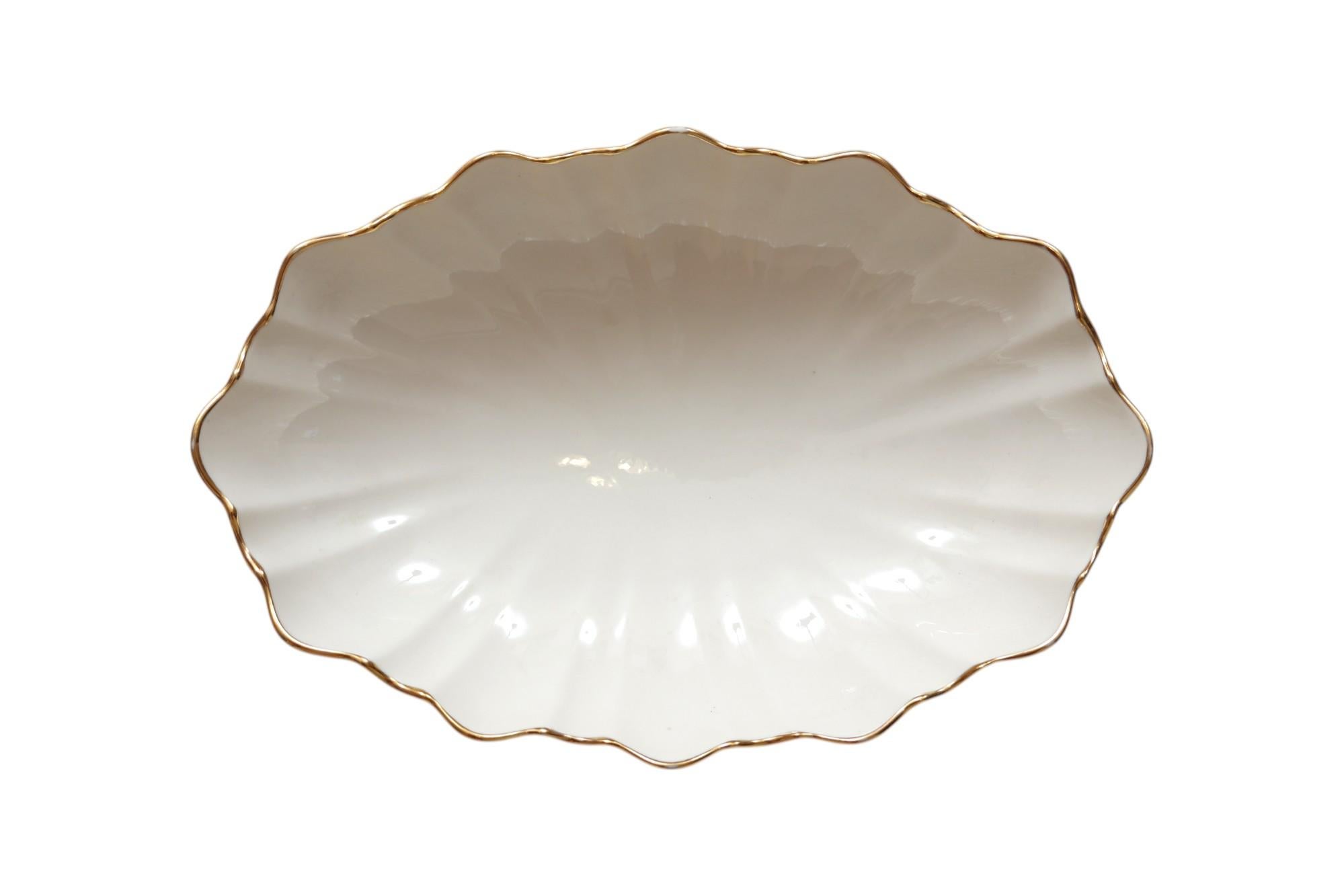 A ceramic scalloped dish by Lenox, made for their Symphony collection circa 2000. The undulating fluted shape is decorated with a gilt trim. Marked underneath ‘Lenox Made in the USA’. 