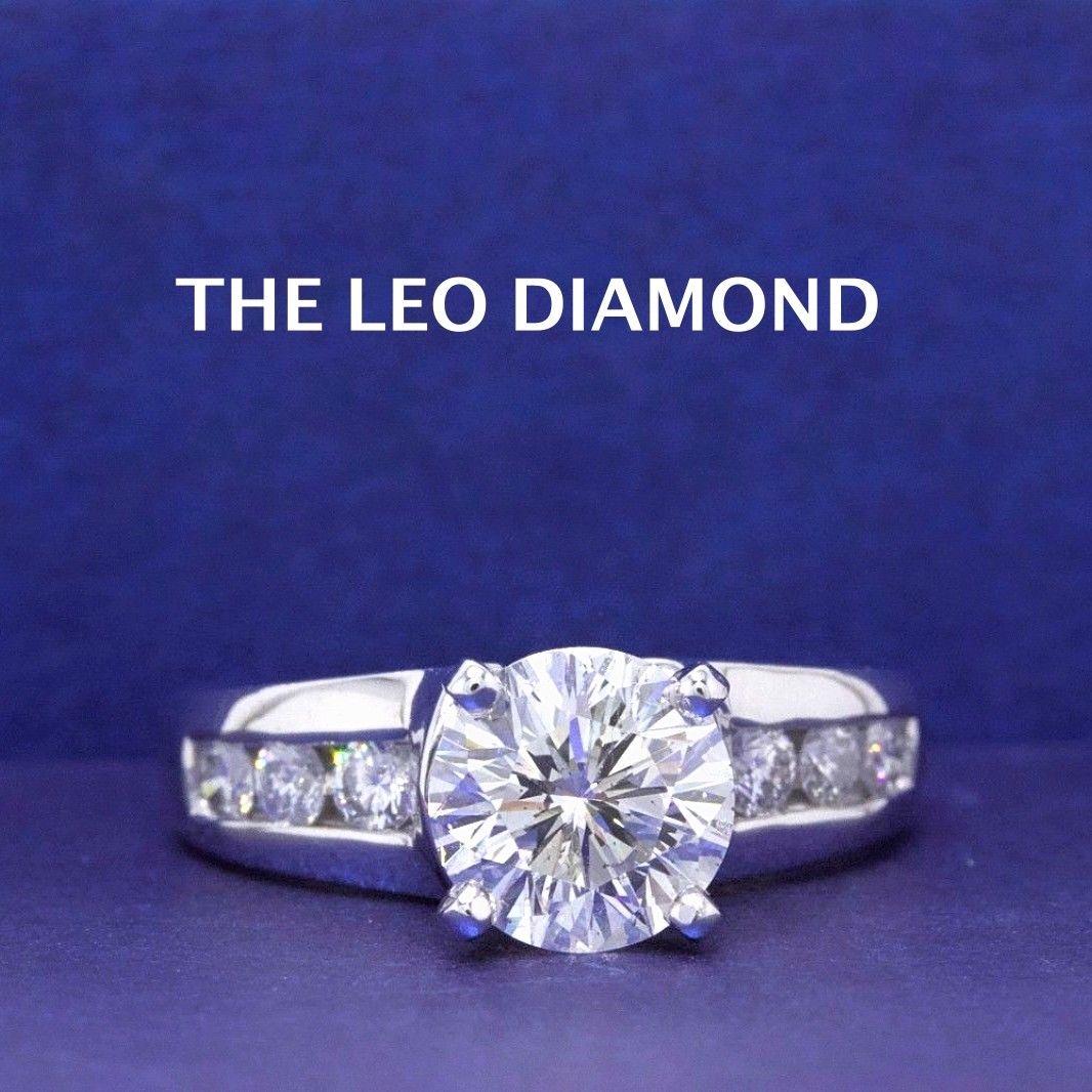 THE LEO DIAMOND 
Style:  Solitaire with Diamond Band Design
Serial Number:  LEO 202875
Certificate:  IGI # 33227859
Metal: 14KT White Gold 
Size:  7.5 - Sizable
Total Carat Weight:  2.10 TCW
Diamond Shape:  Leo Round  1.54 CTS - H Color - SI2